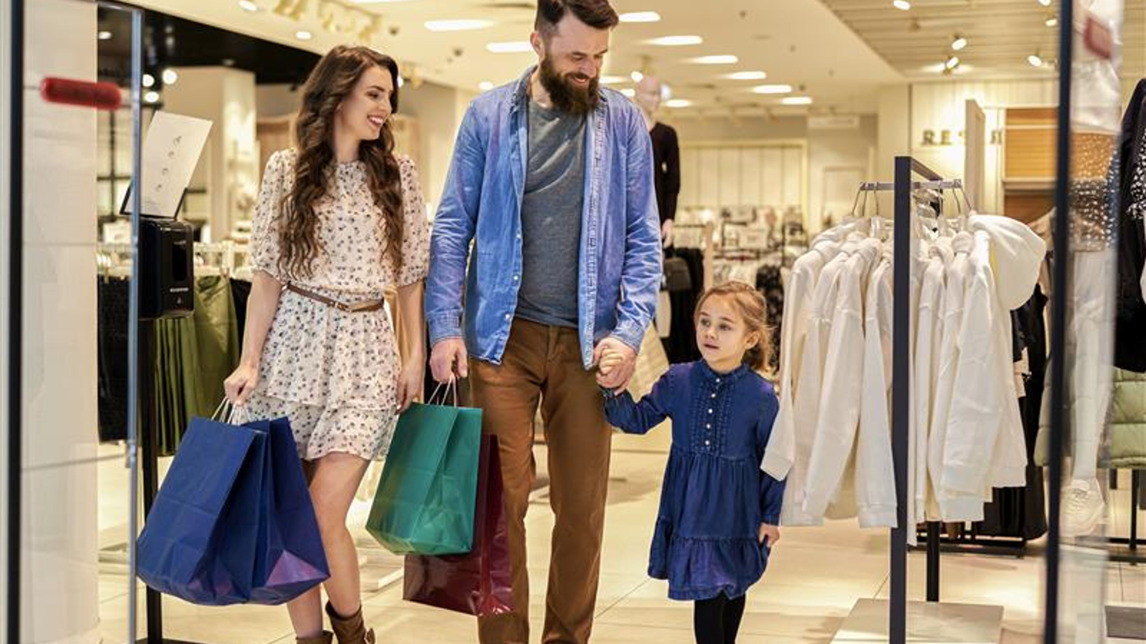 Two modern girls, one holding shopping bags while the other looks at her phone.