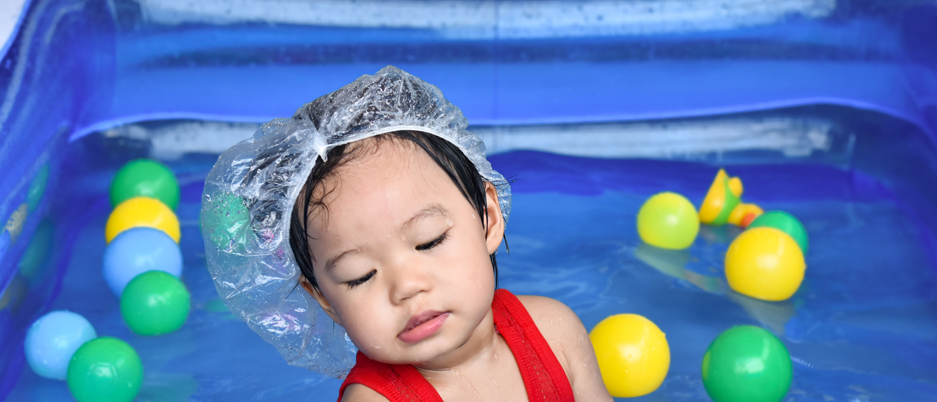 baby boy plays in the pool full of colorful balls