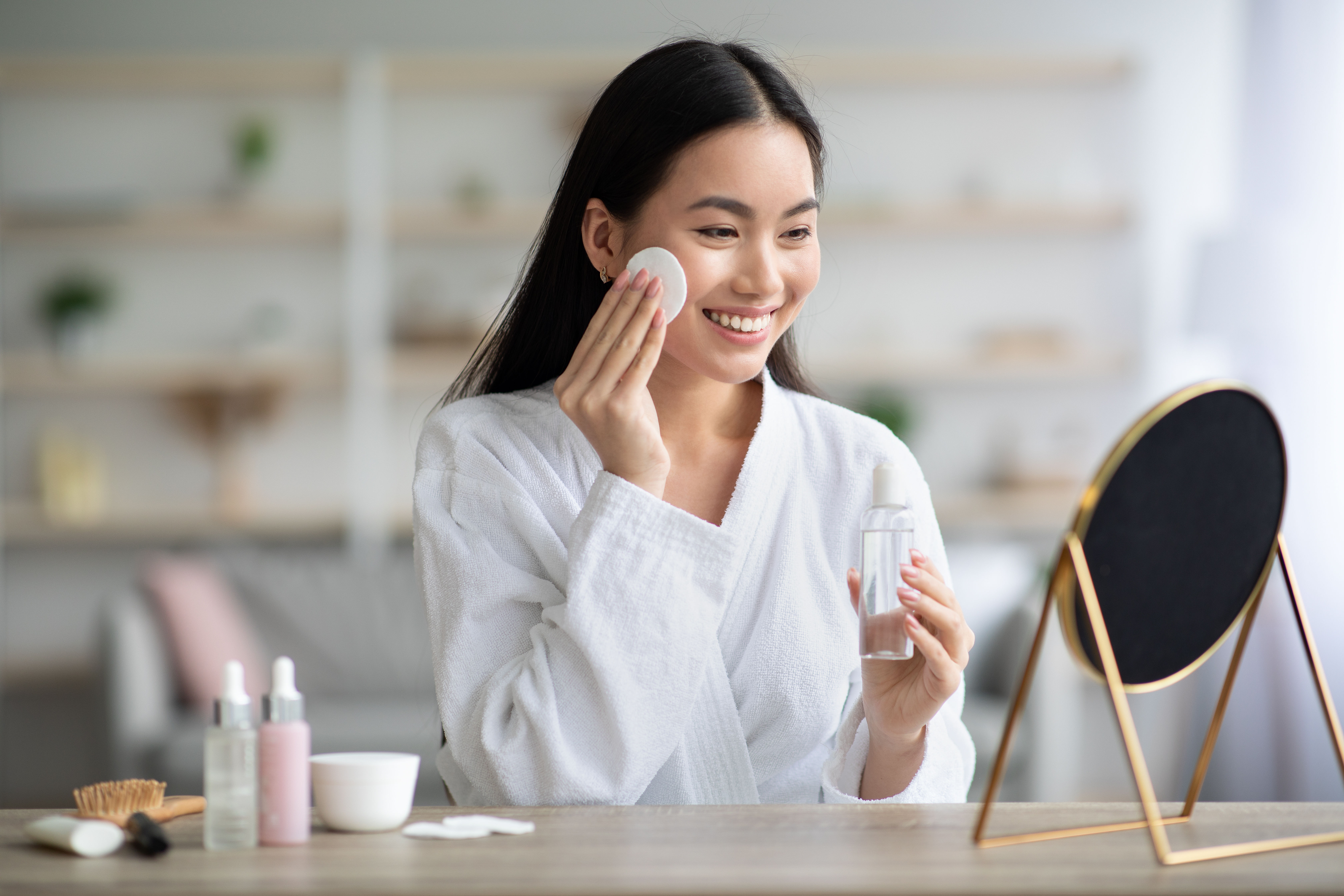 Cheerful asyano babae paglilinis kanya mukha may toner 