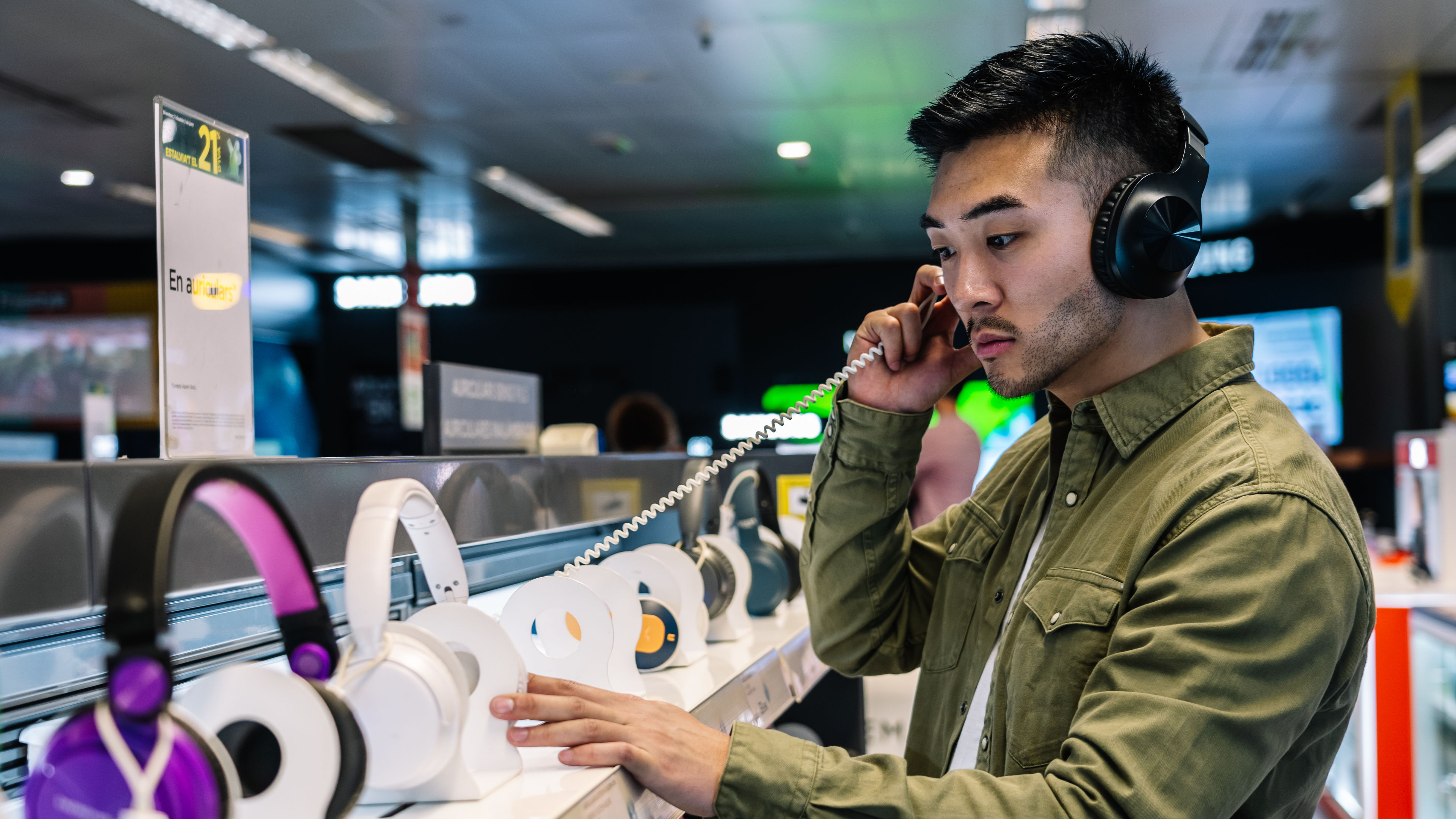 Focused ethnic man choosing headphones in store 