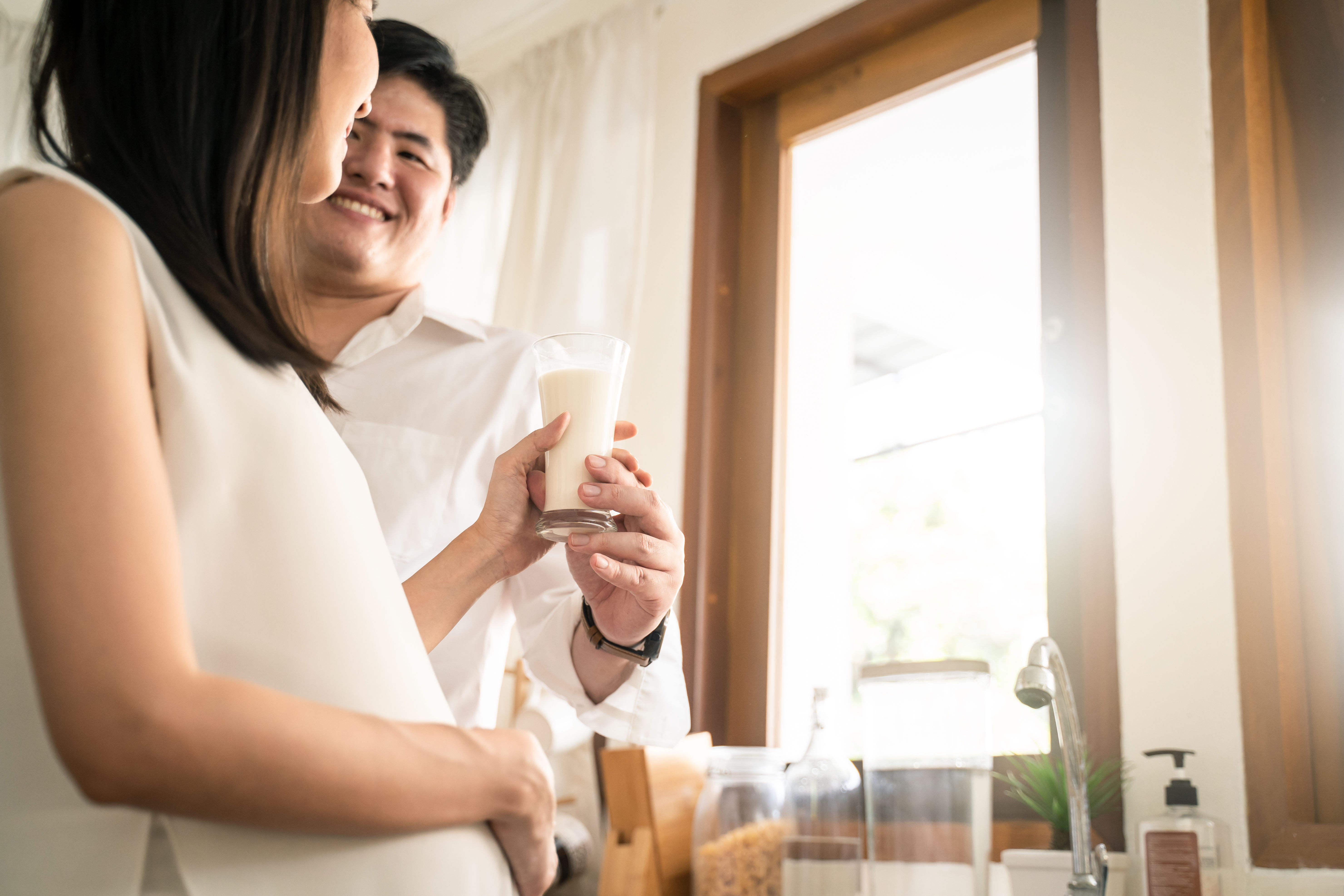 Masayang pamilya, asyano bata mag asawa alagaan buntis na babae sa pamamagitan ng pagbibigay ng gatas sa kusina 