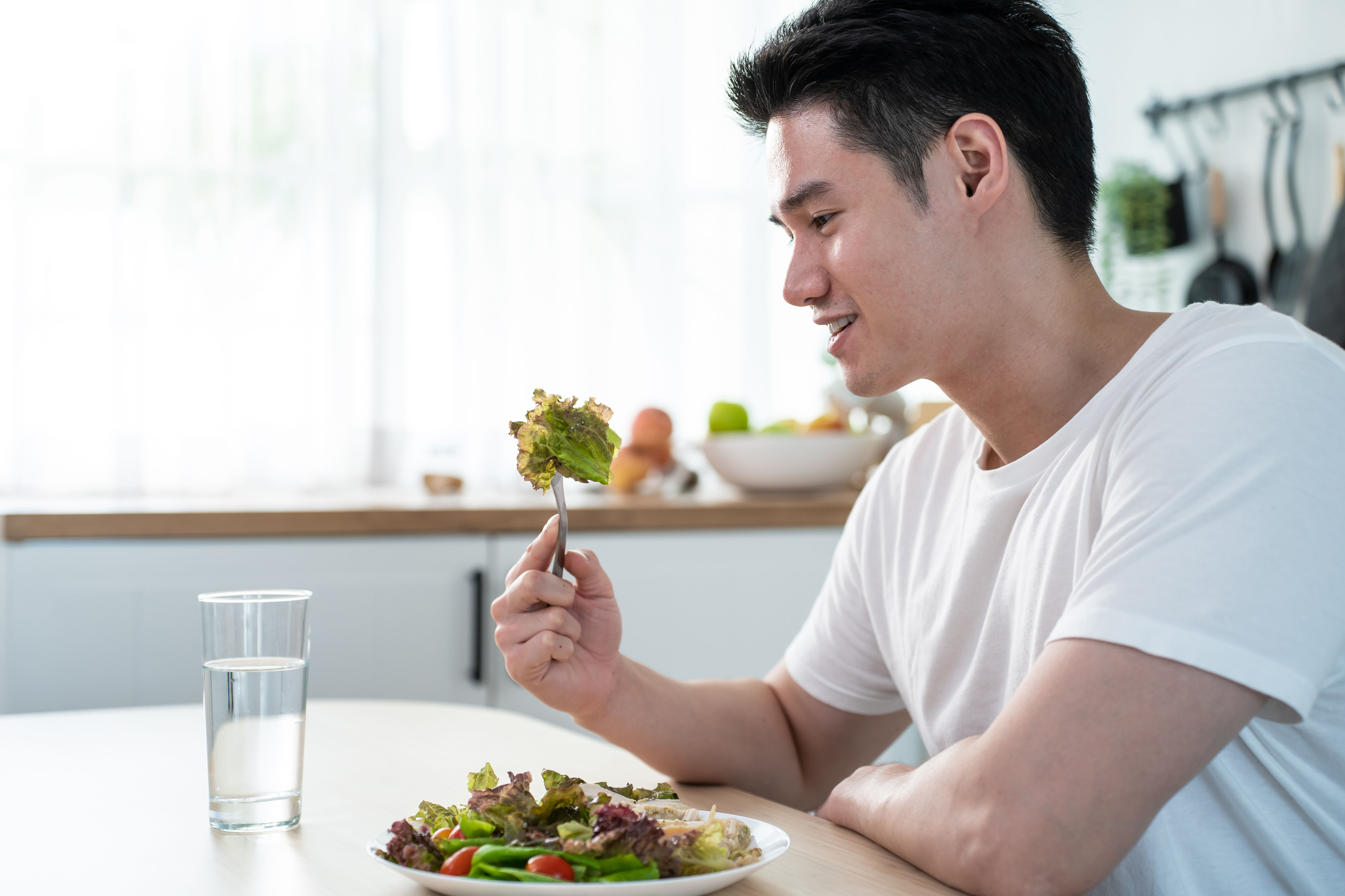 Lalaki kumakain ng salad sa bahay 
