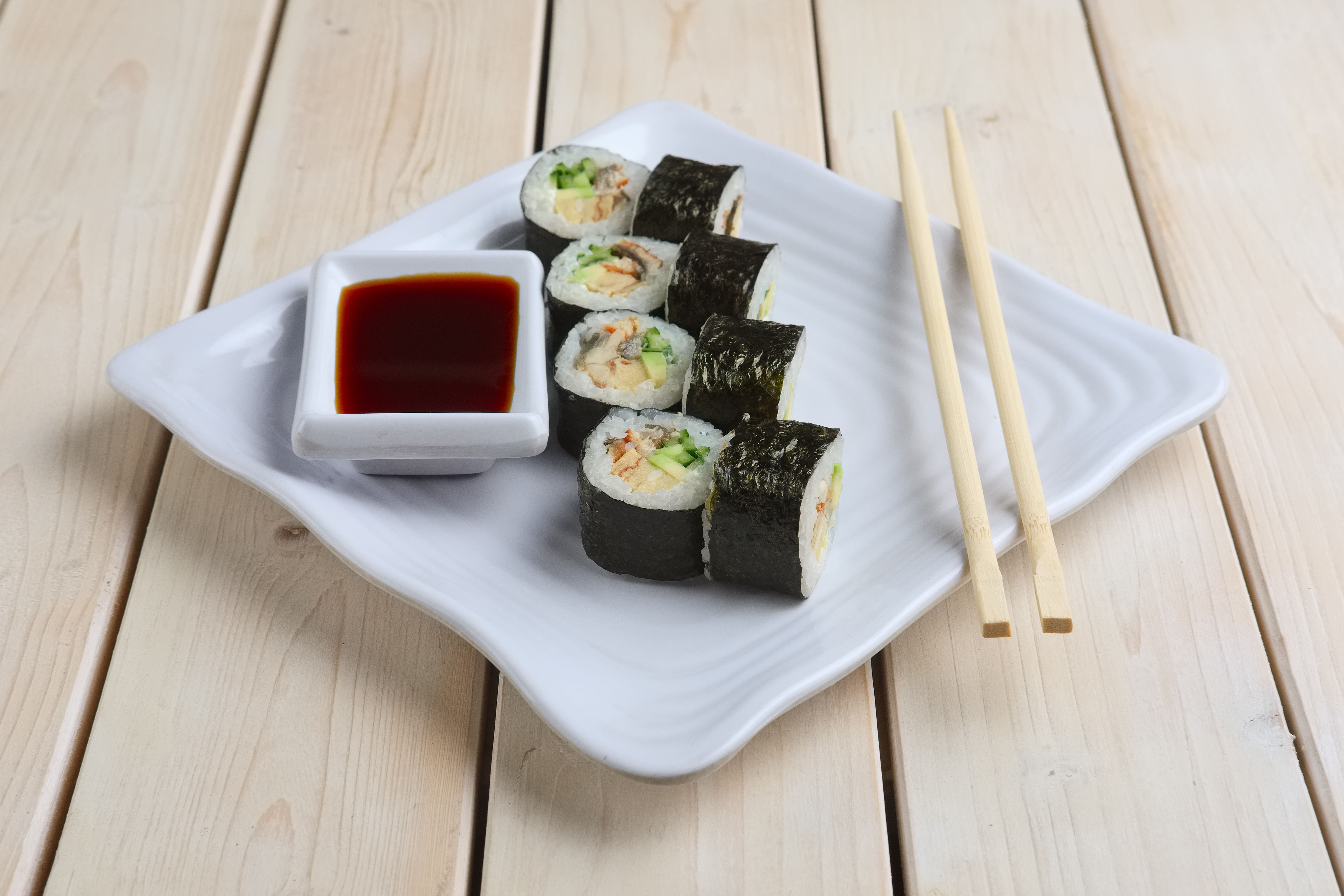 Set ng mga roll na may salmon, abukado at pipino sa plato na may toyo 