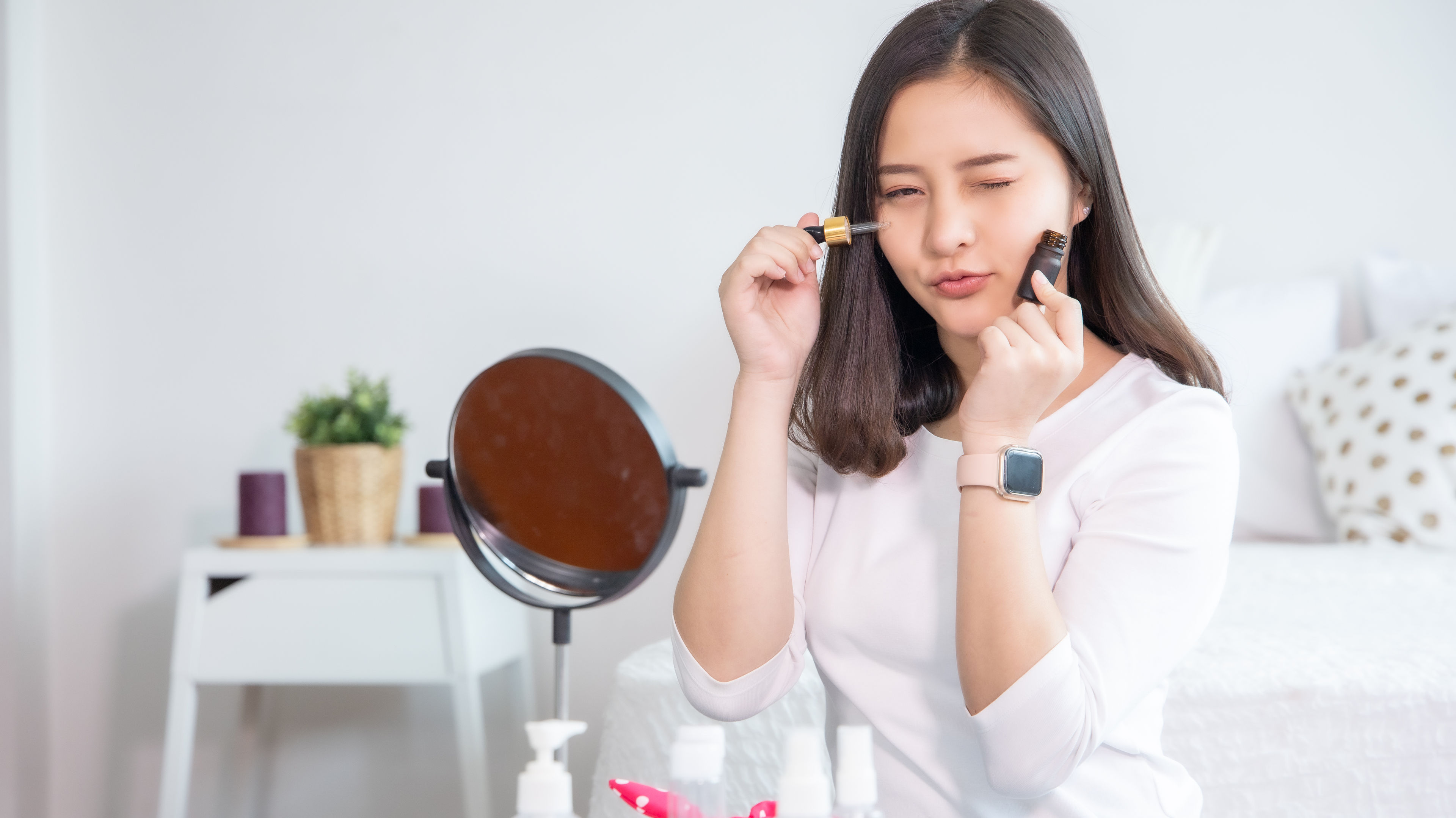 Portrait of young Asian woman using cosmetics at home.