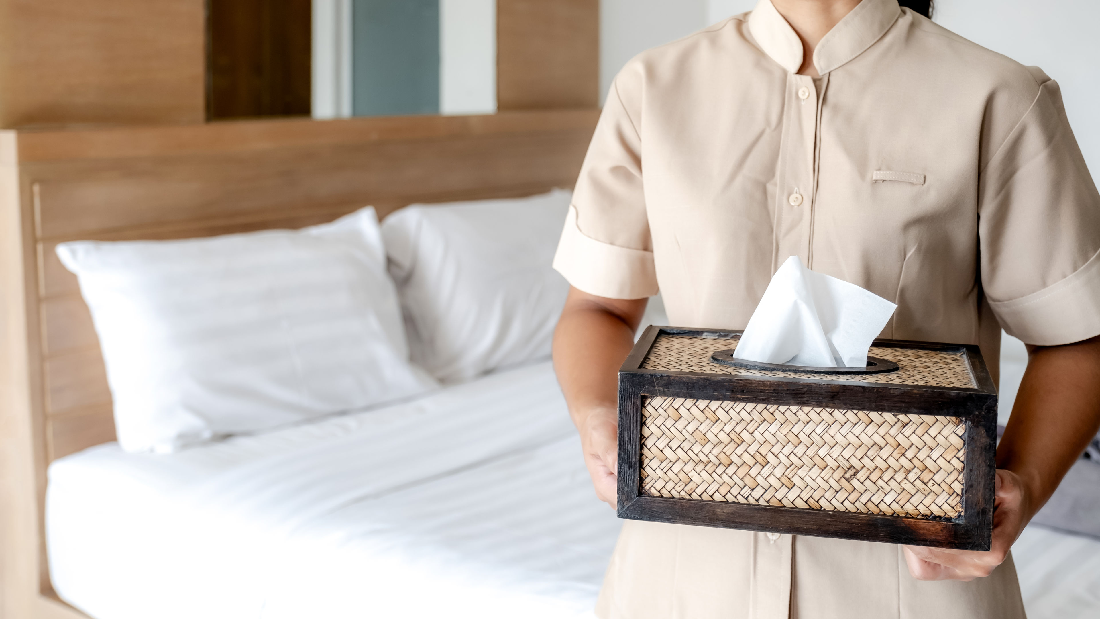 The hotel housekeeper in uniform is preparing tissue for use in the bedroom