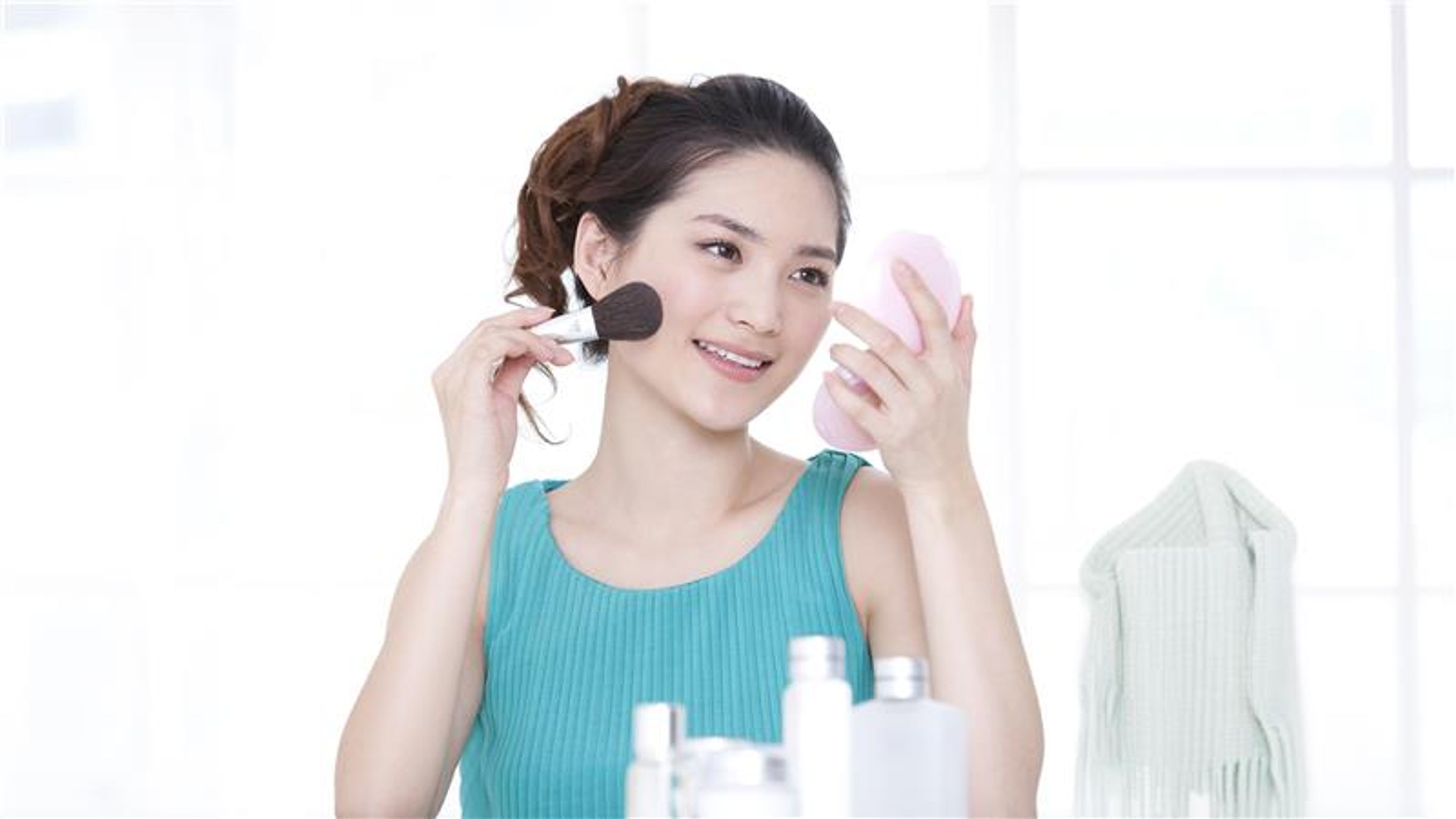 A happy woman skillfully applying makeup with a radiant expression.