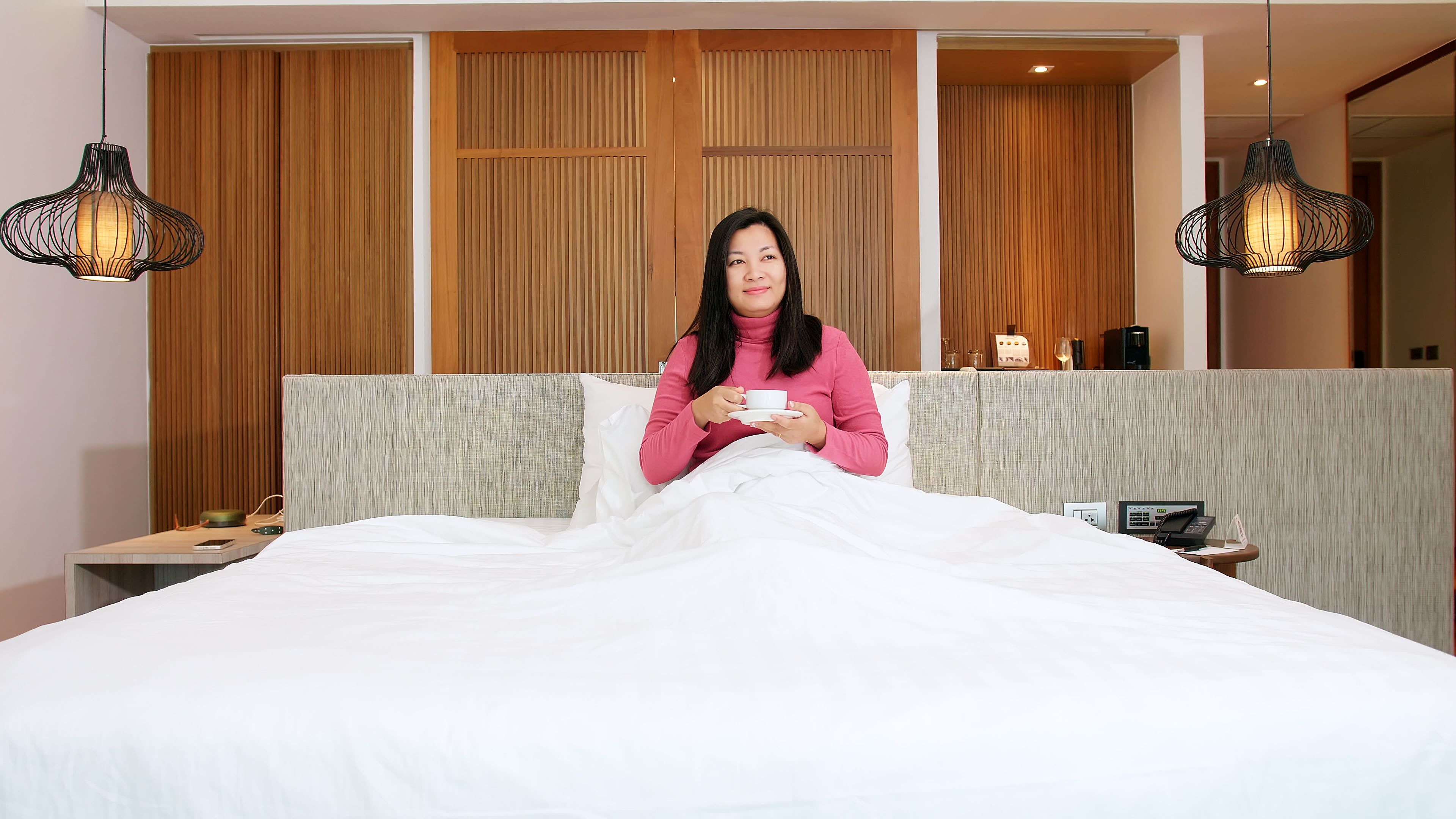 Beauty Asian women are resting in bed and drinking coffee in the morning