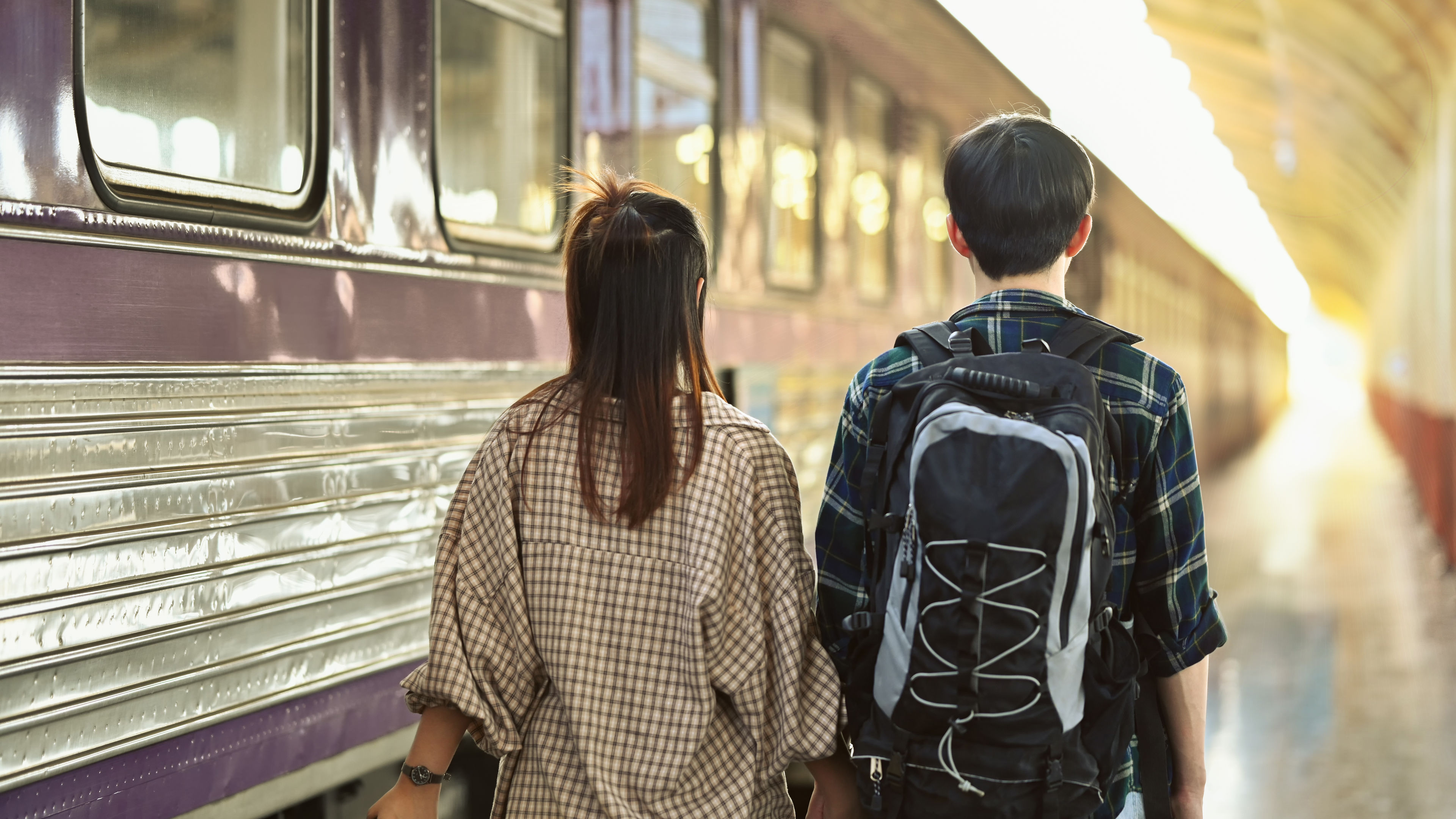 Rearview of young couple walking at the train station platform