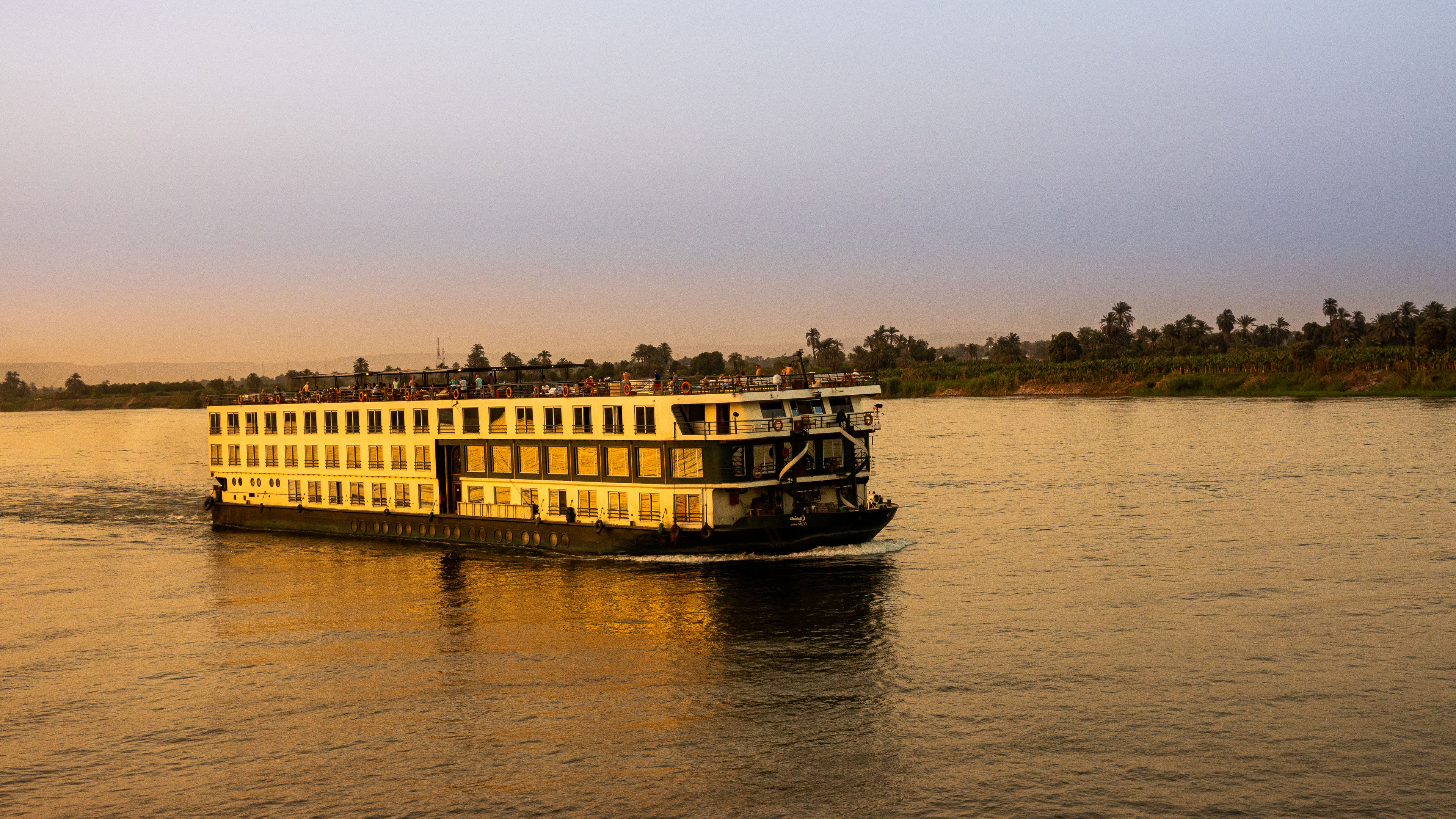 A large cruise ship is sailing on a wide river