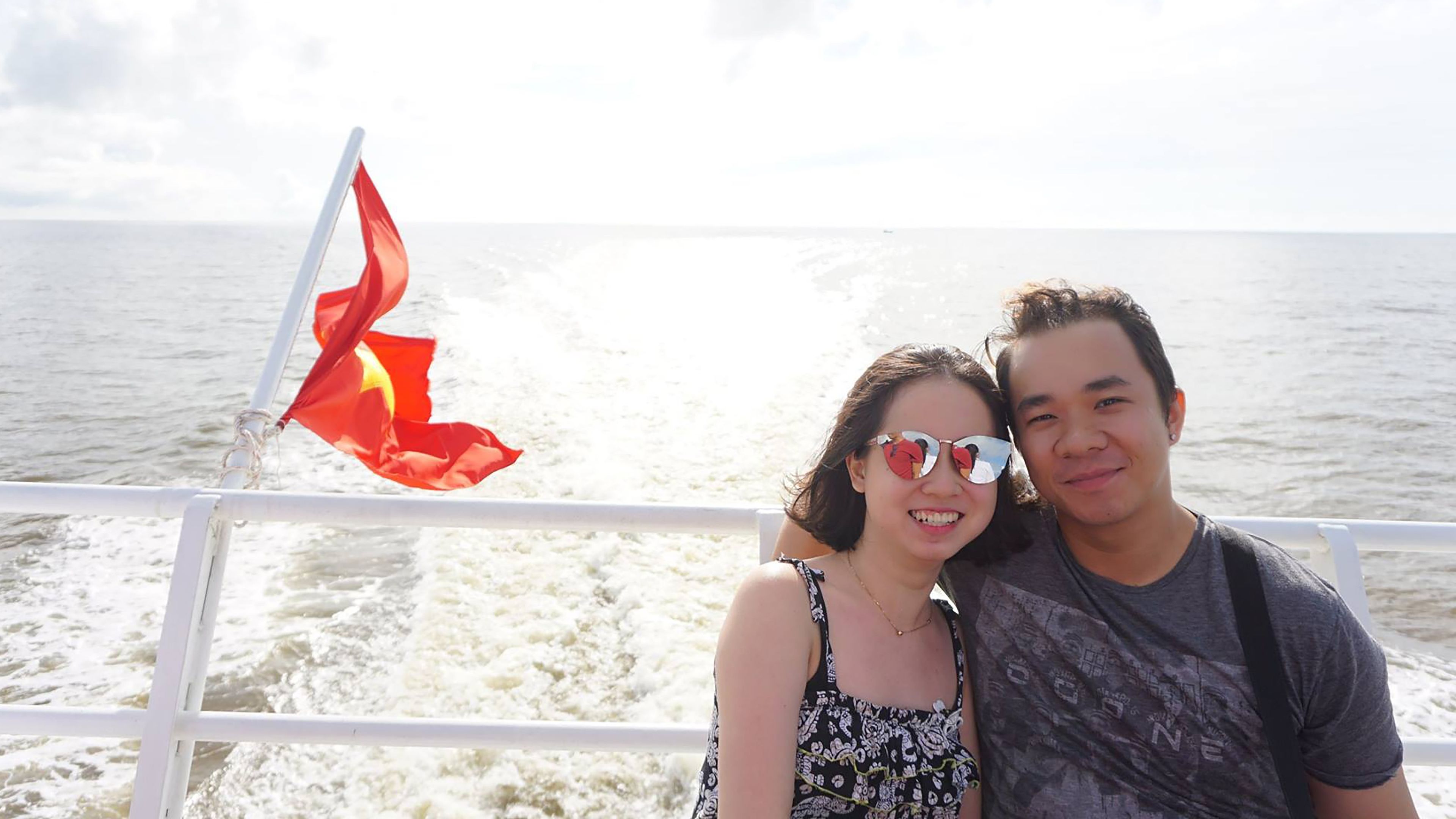 A smiling couple is sitting on the deck of a boat