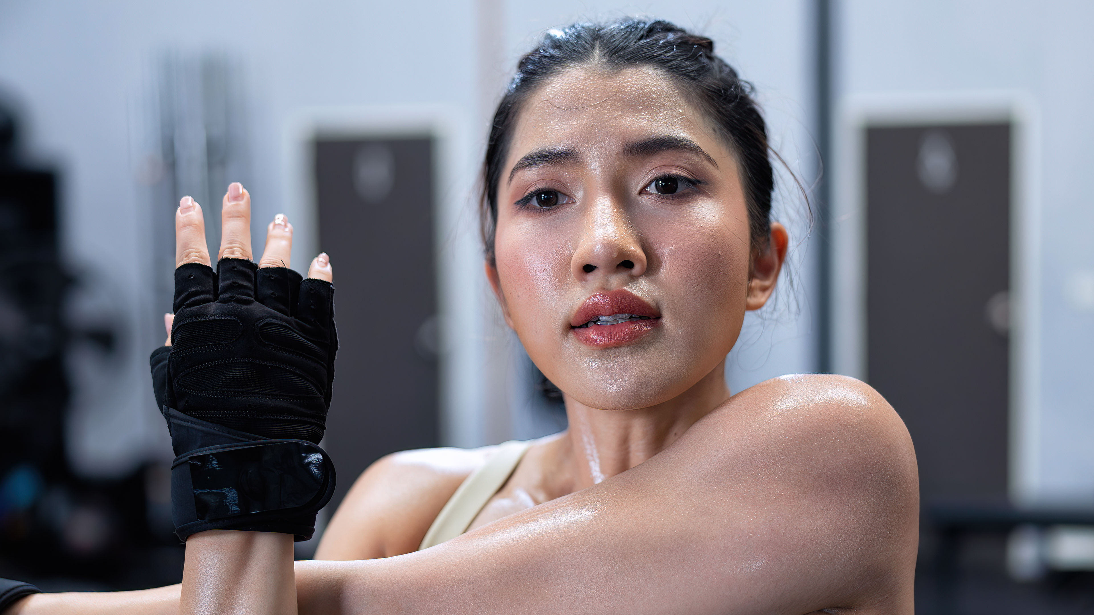 A young woman is wearing black workout gloves