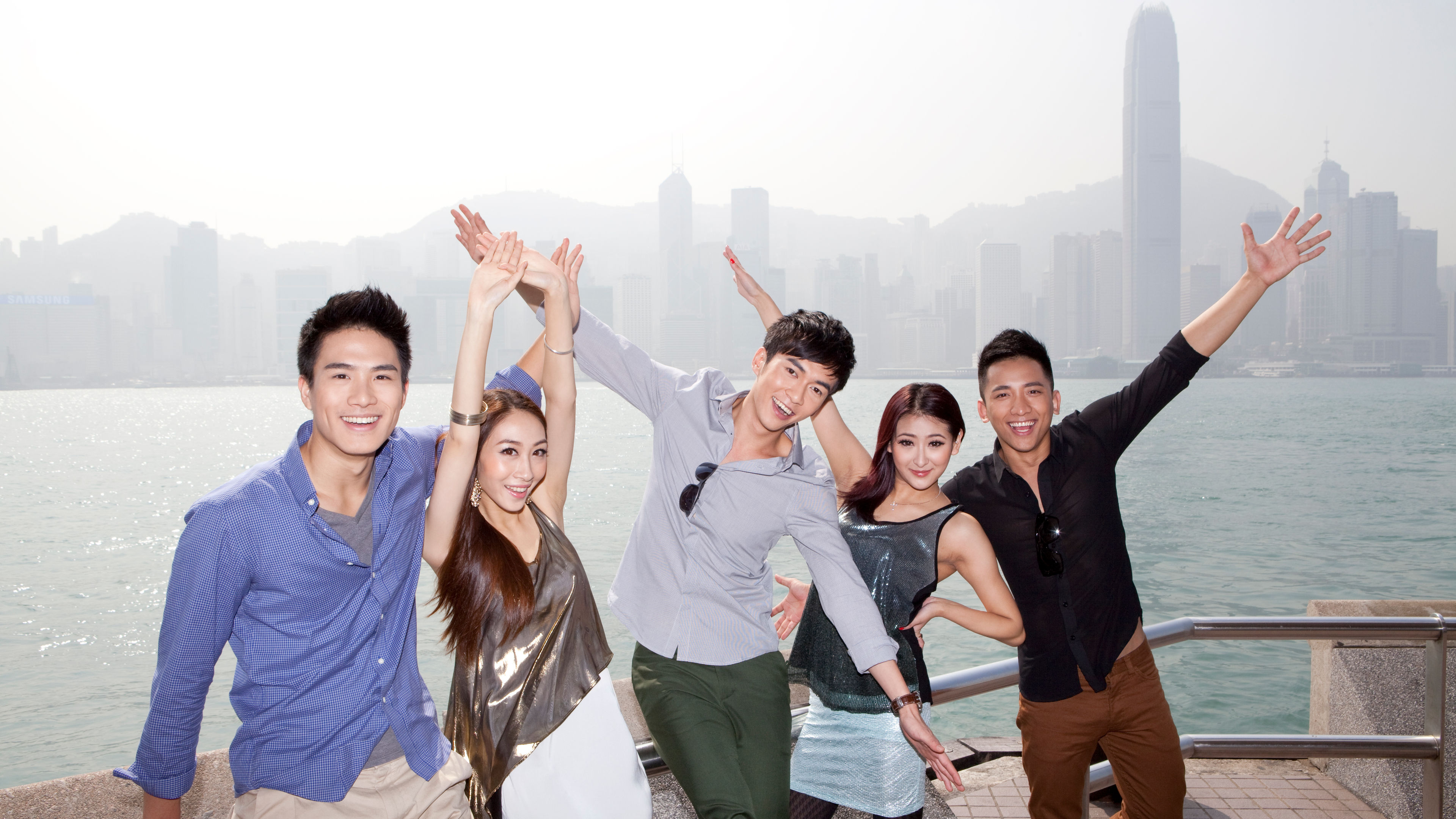 Cheerful young friends appreciating the spectacular view of Victoria Harbor, Hong Kong