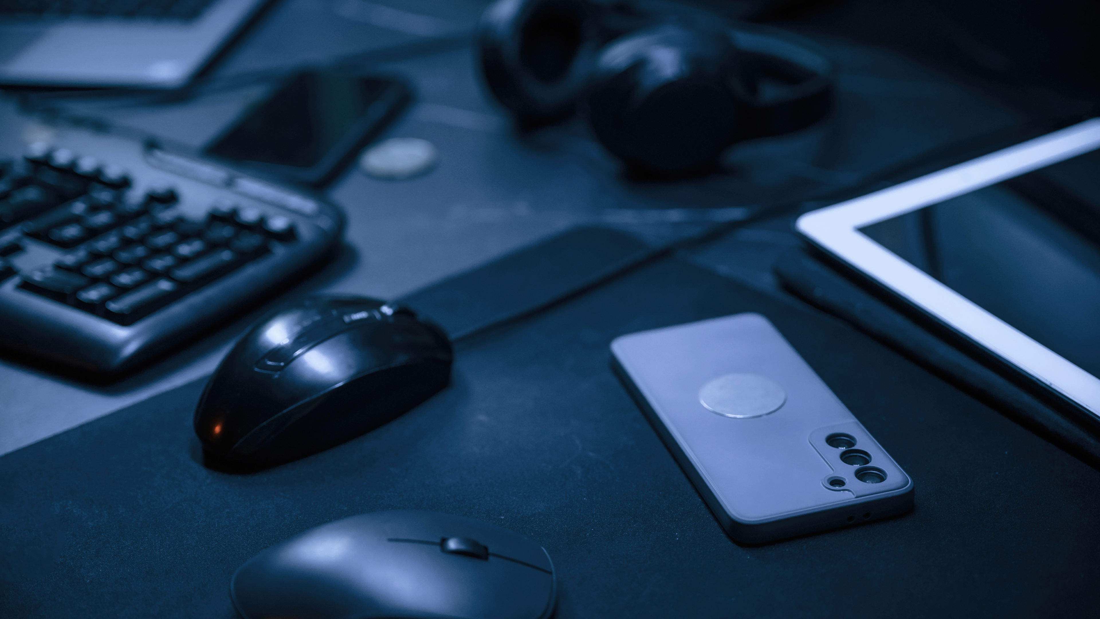 Close up view of table with smartphone, pc mouse, keyboard and headphones