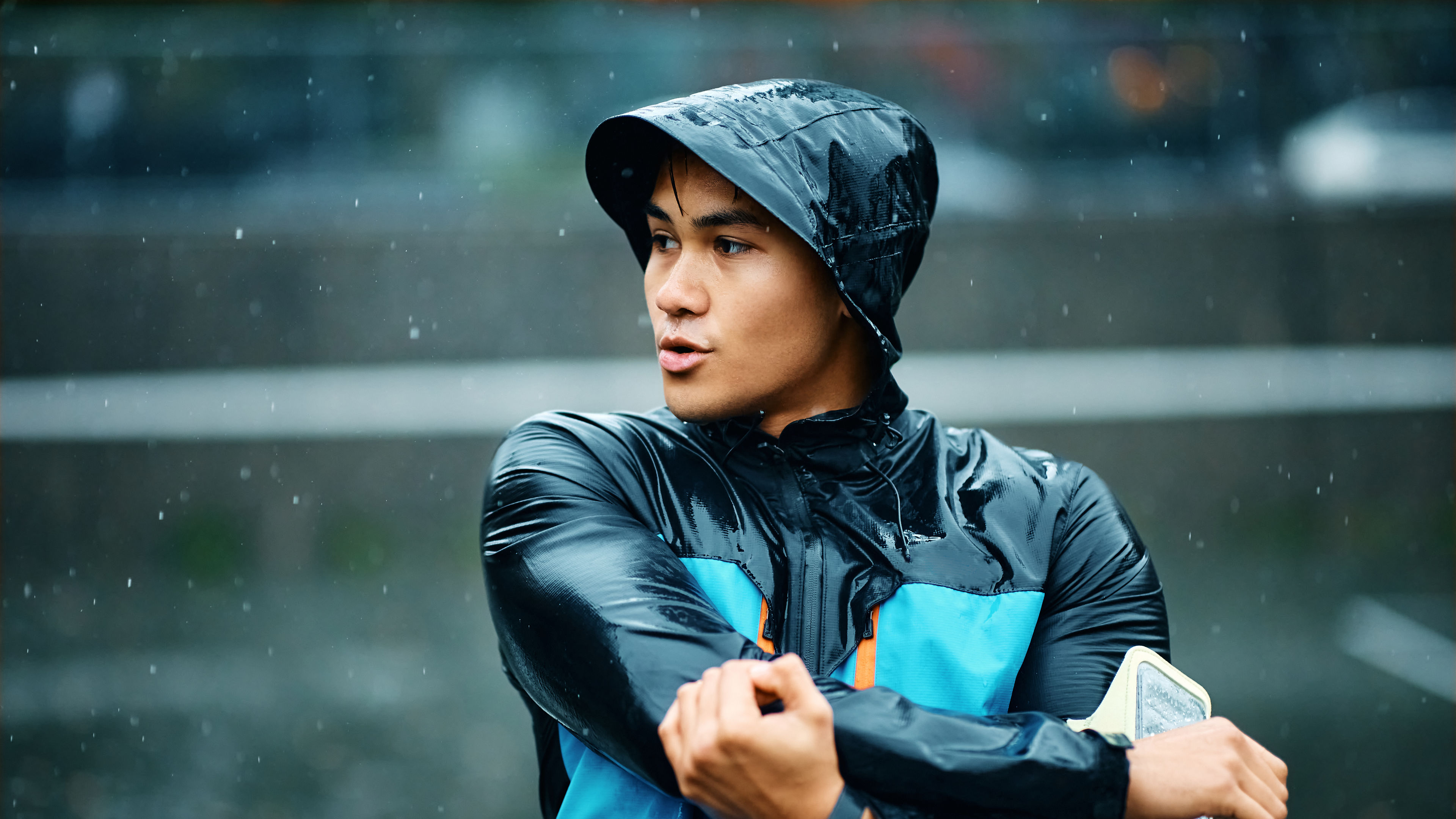 Young athletic man warming up for exercising during rainy day