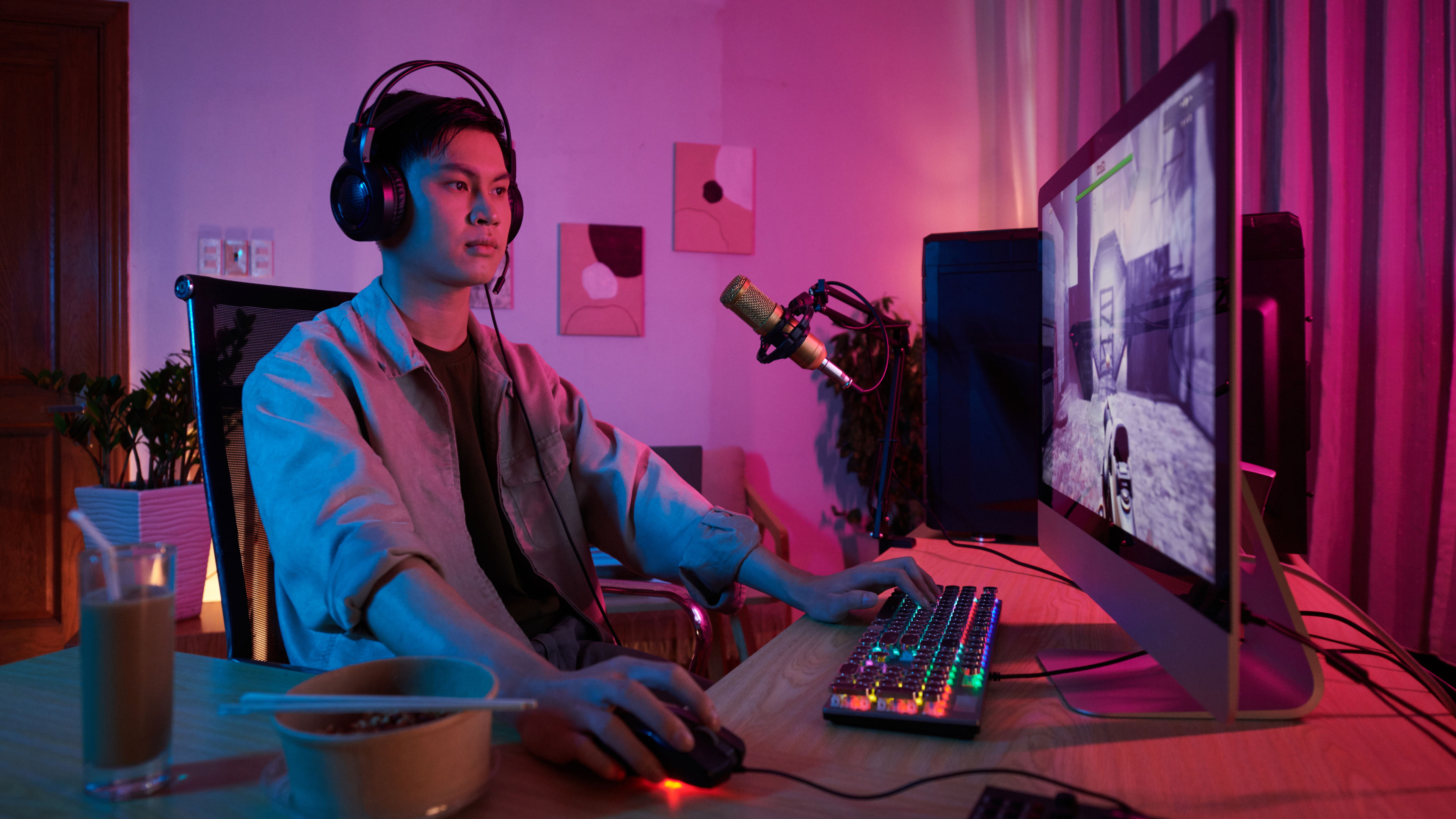 Asian video gamer playing first person shooter game in his computer. 