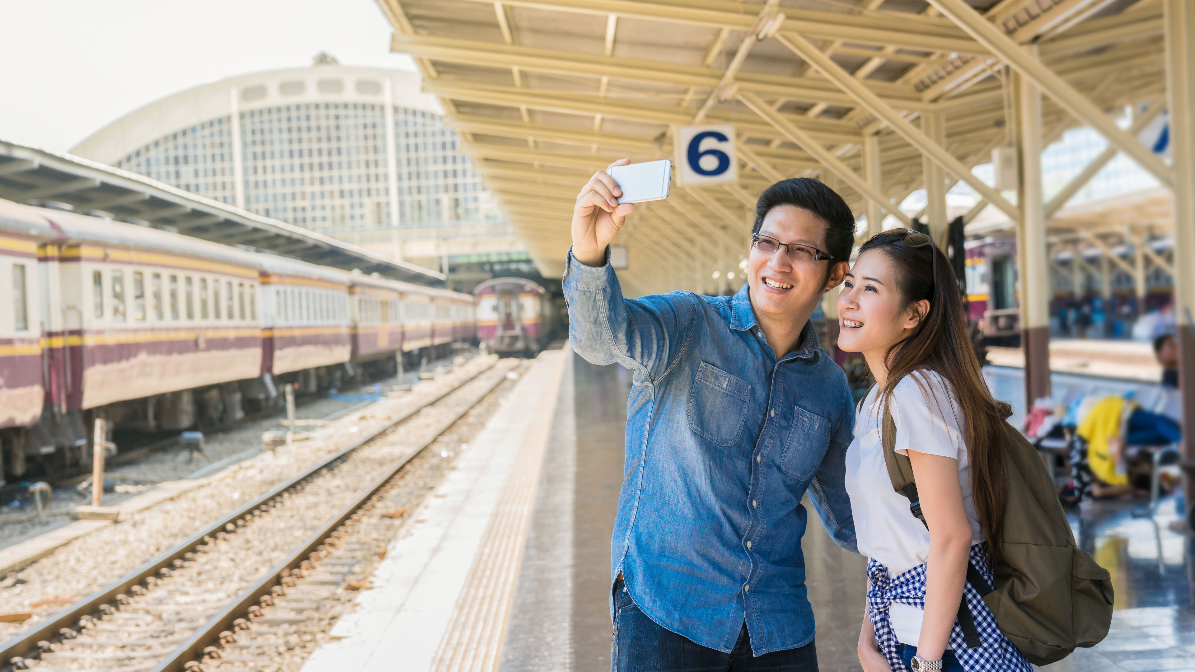 A couple of Multiethnic Travellers are taking a selfie photo of themself at the train station