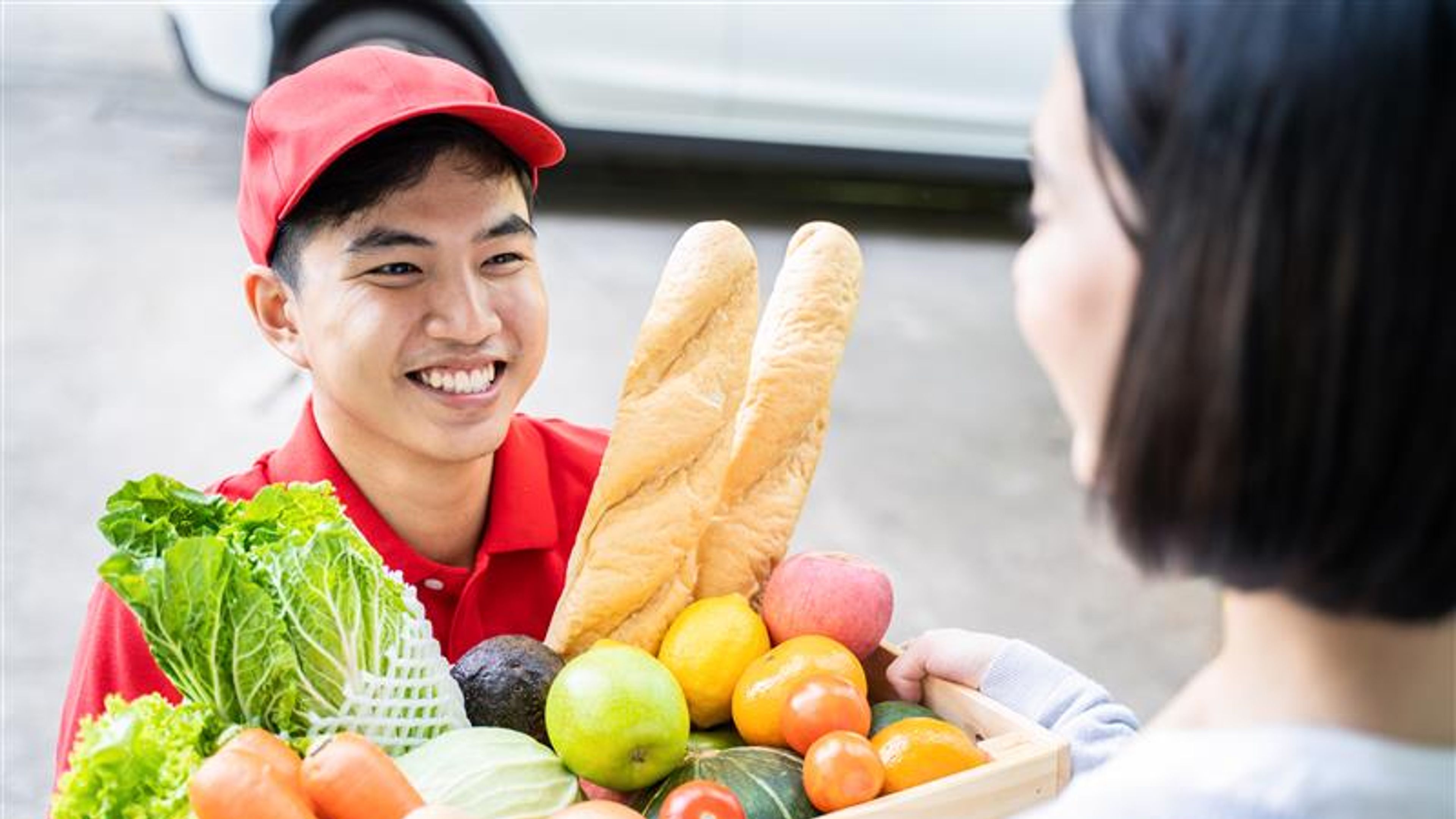 Asian deliver man worker in red color uniform handling bag of food.