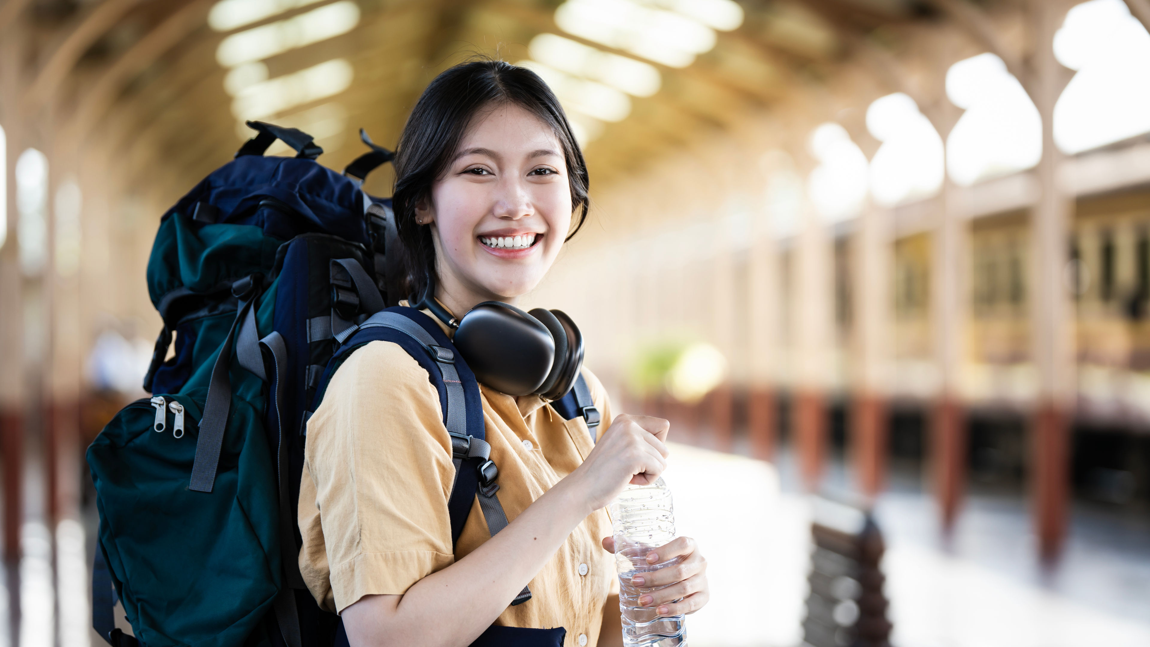 Beautiful asian woman with a backpack standing at the Train Station Platform