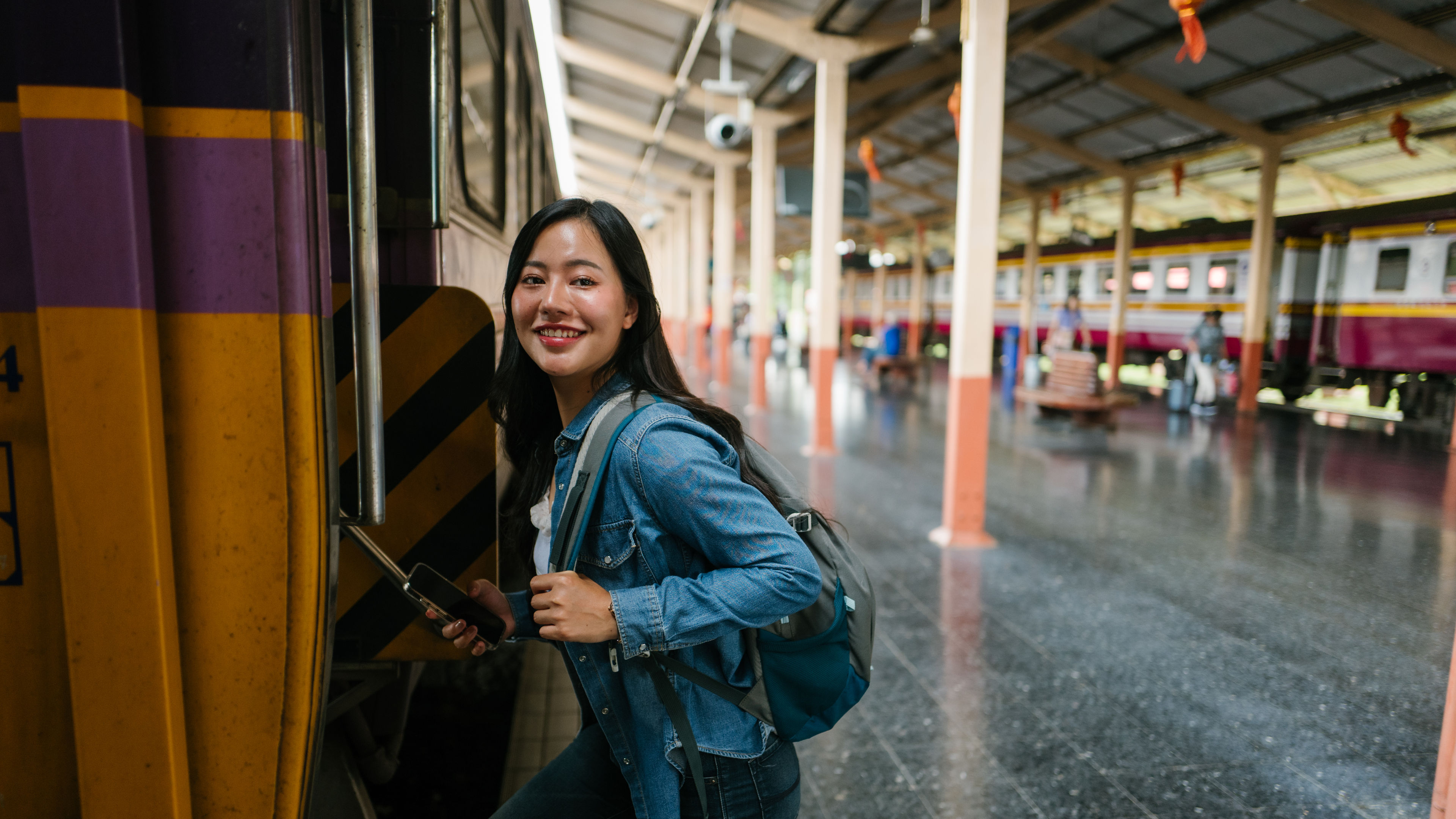 Smiling tourist boarding a train at Hua Lamphong Station in Bangkok, Thailand