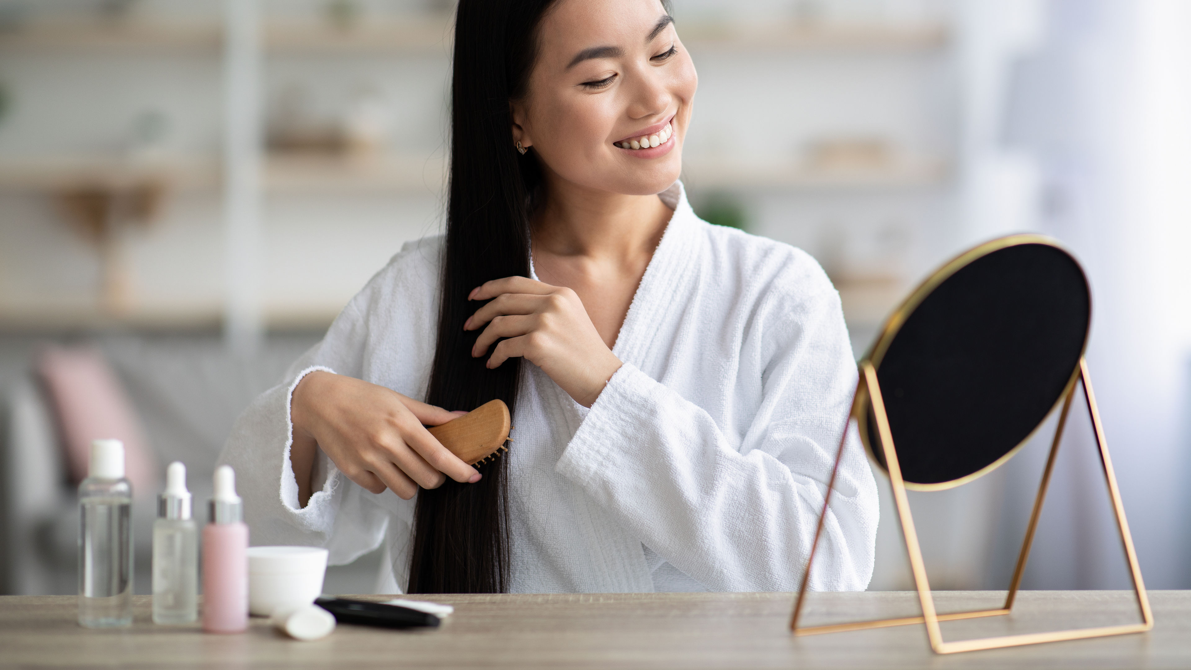 A happy woman combing her hair with a wooden brush 