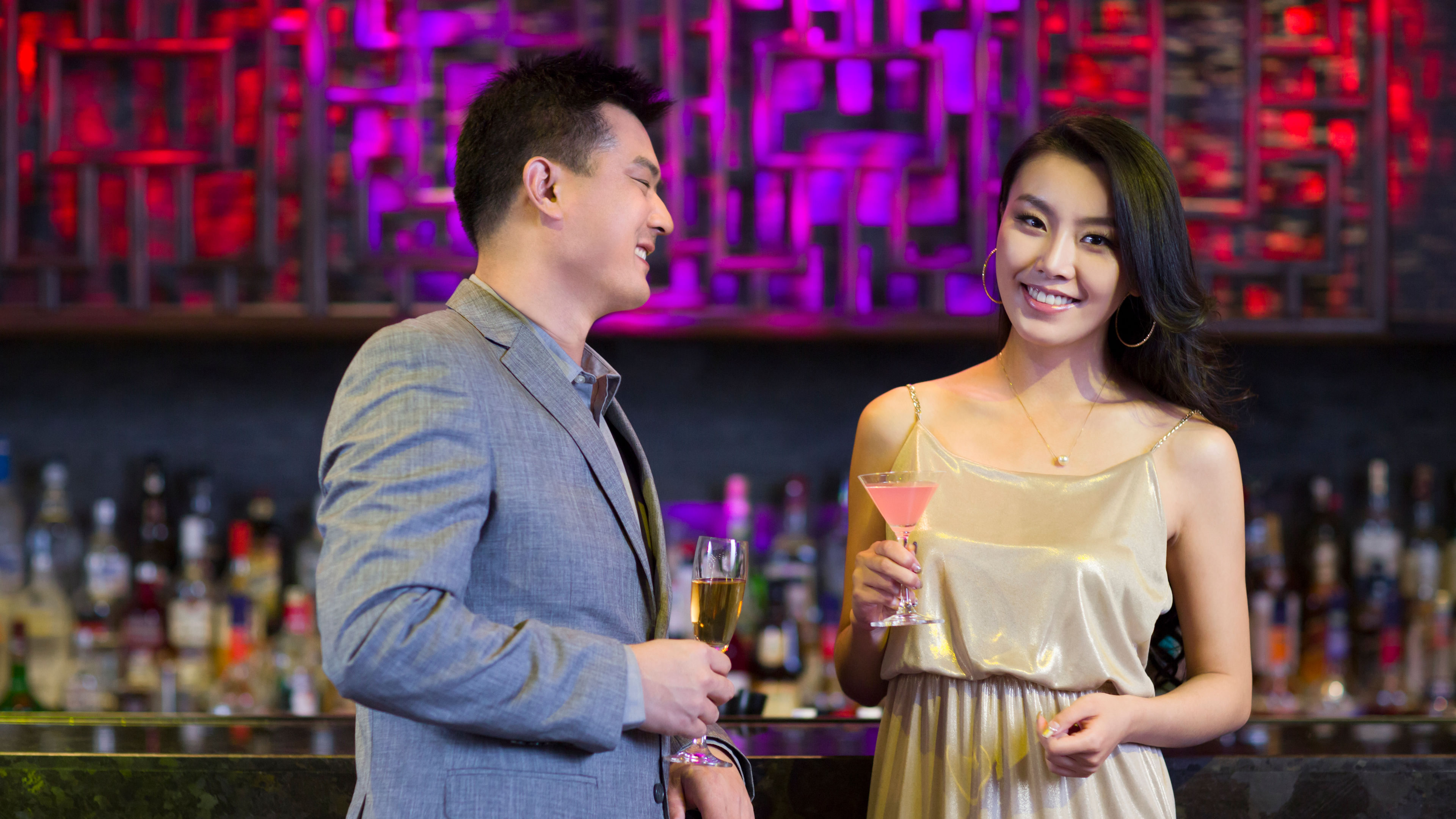 A well-dressed man and woman are enjoying drinks together