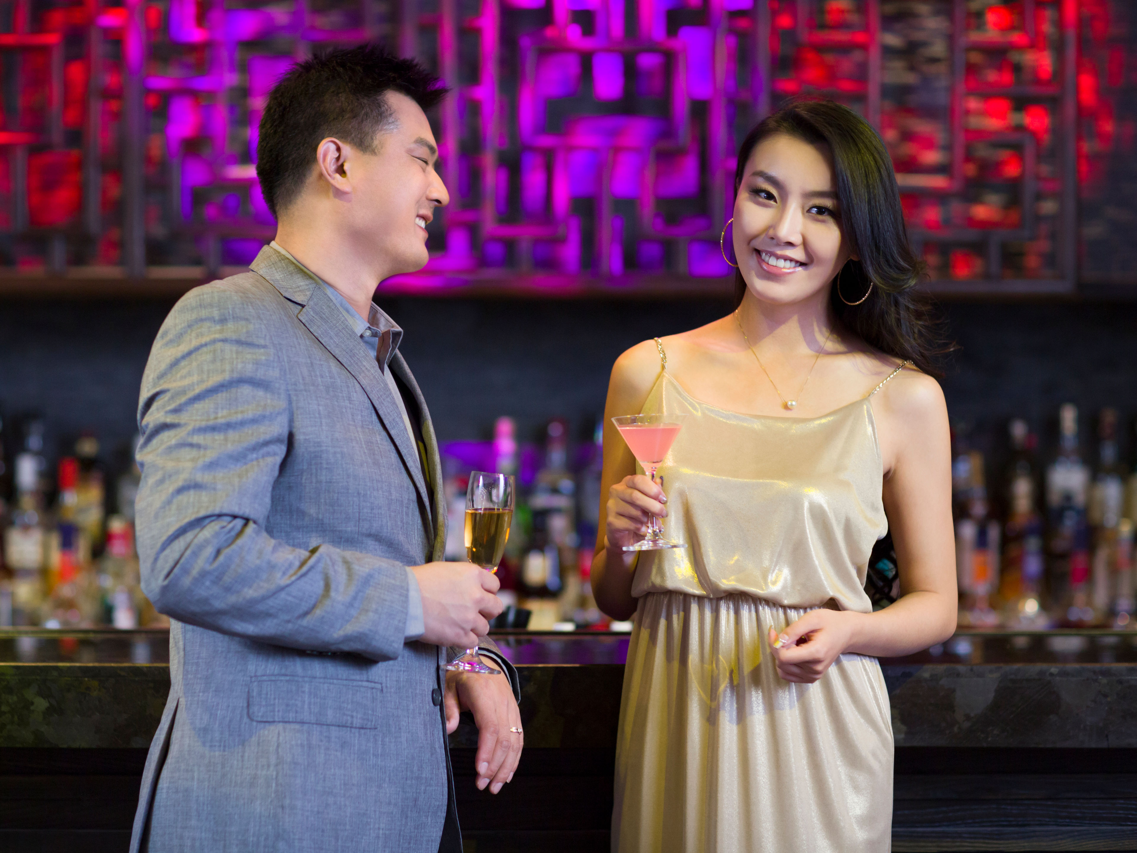 A well-dressed man and woman are enjoying drinks together