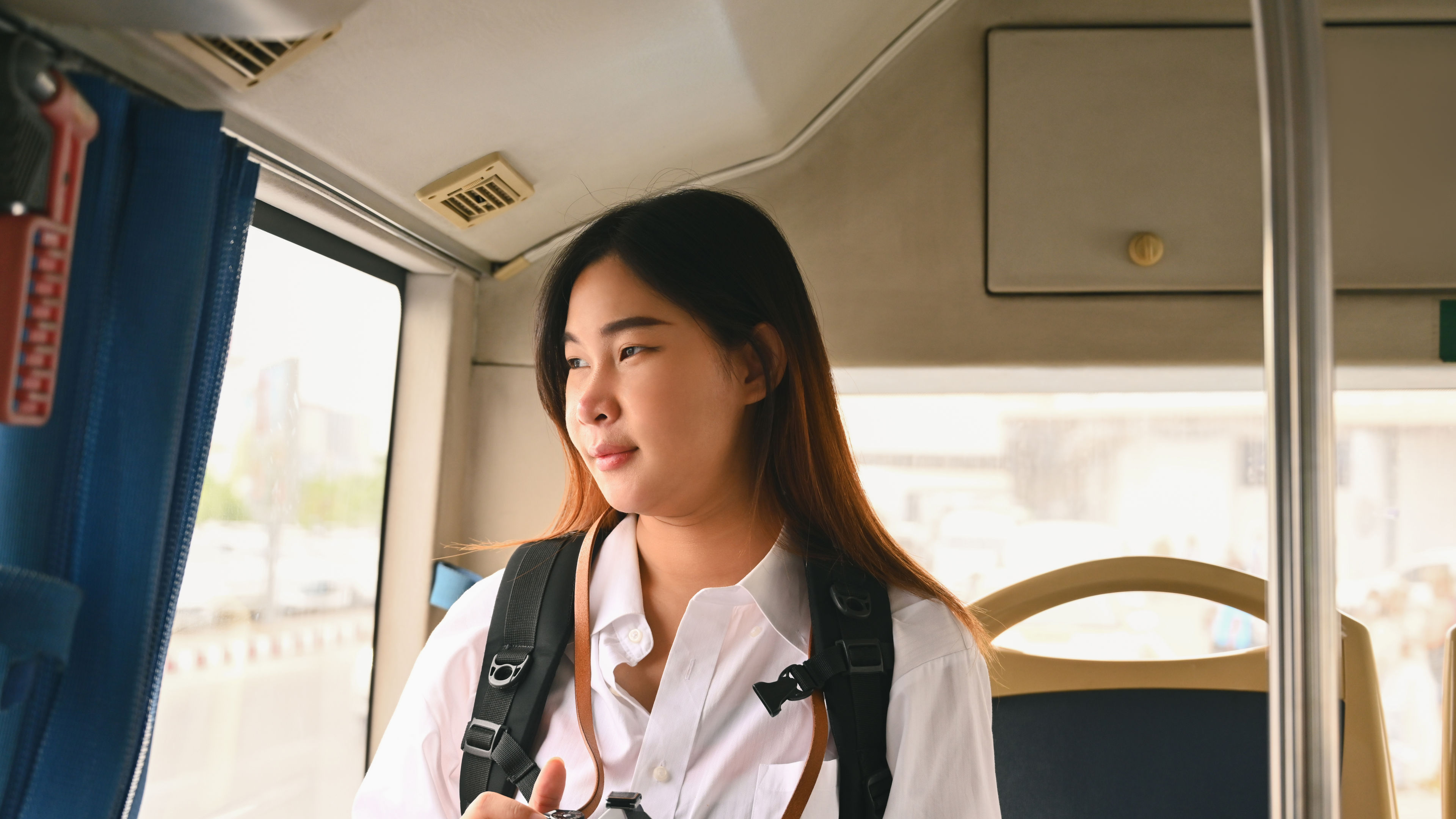A young woman looks out the window of a bus. 
