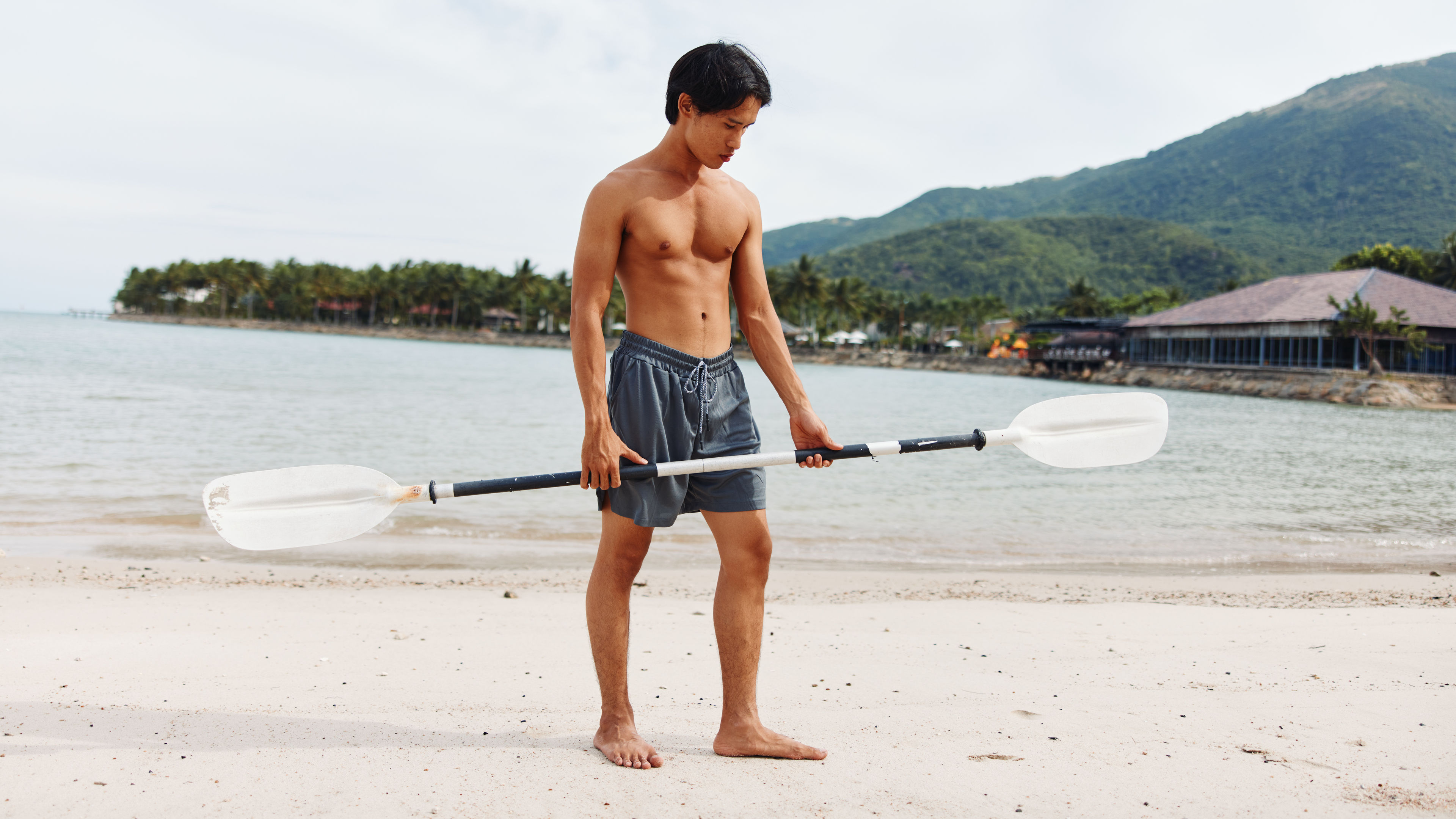 Man holding kayak paddle on the beach