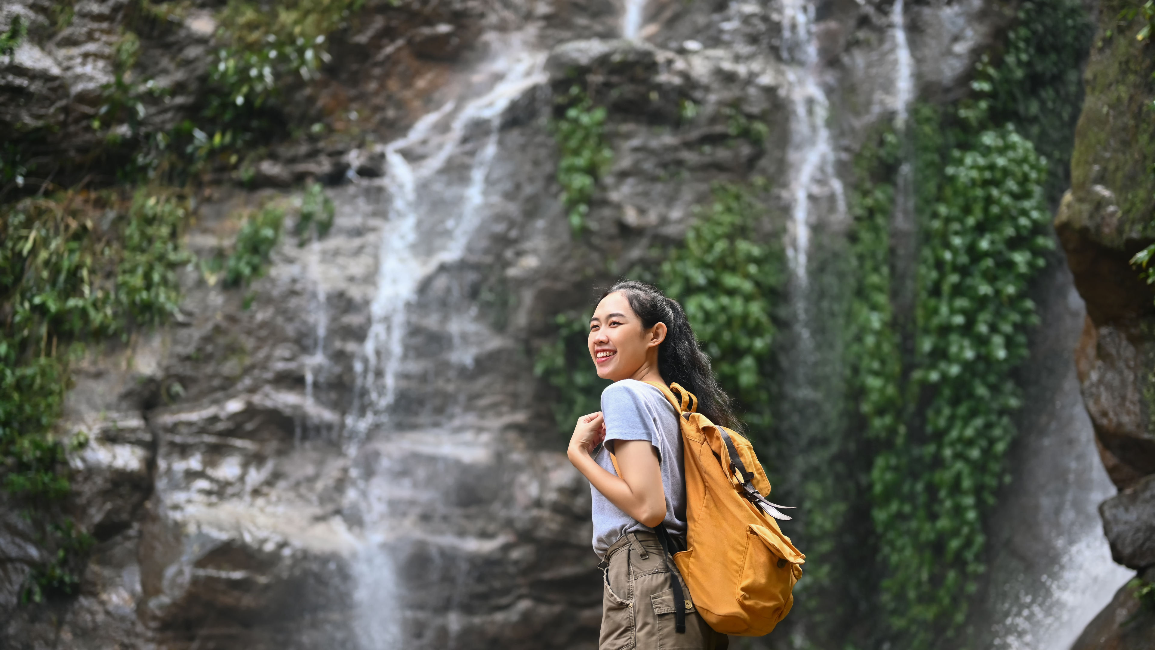Smiling female tourist by waterfall
