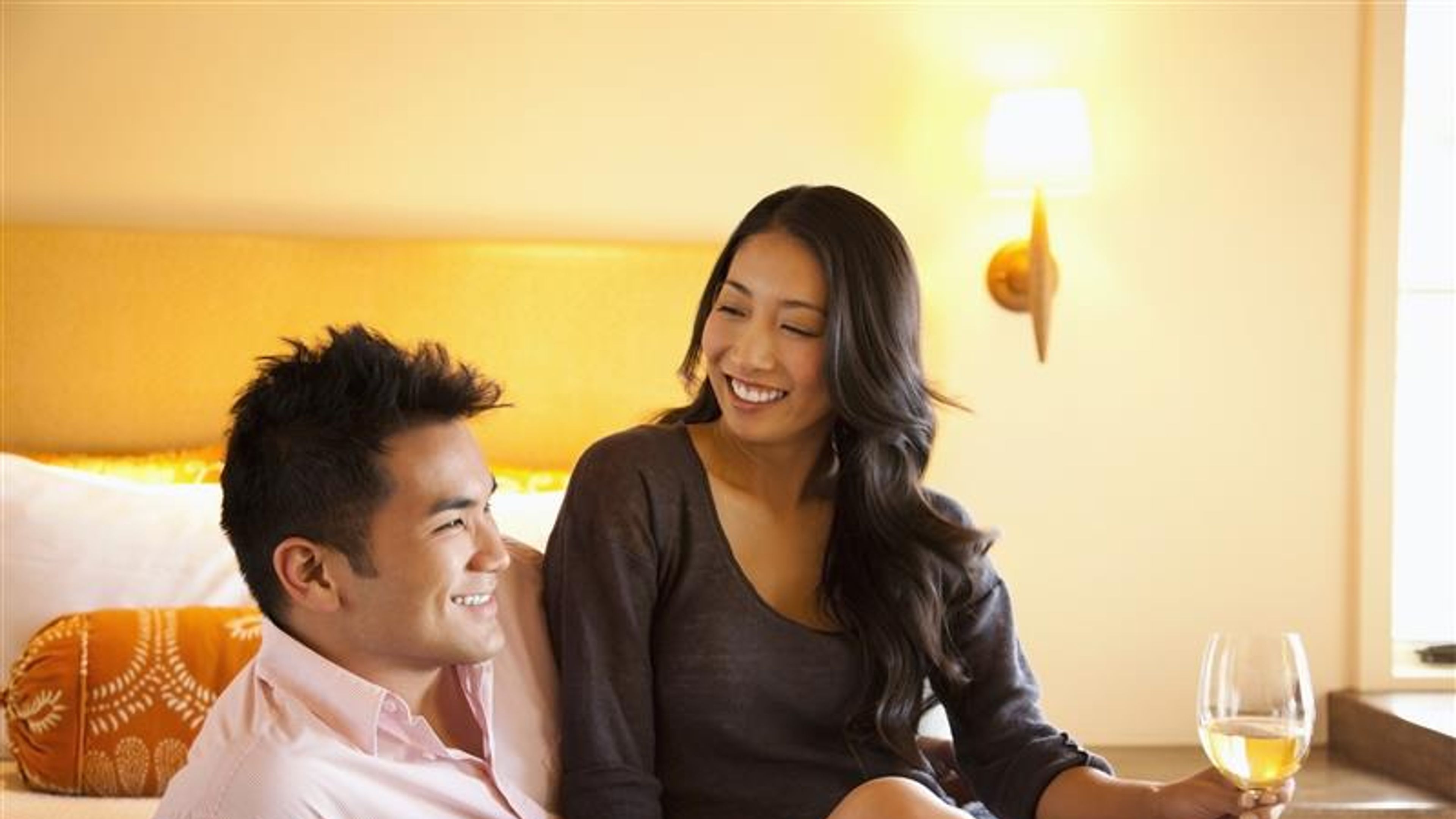 A couple drinking wine in a hotel room.