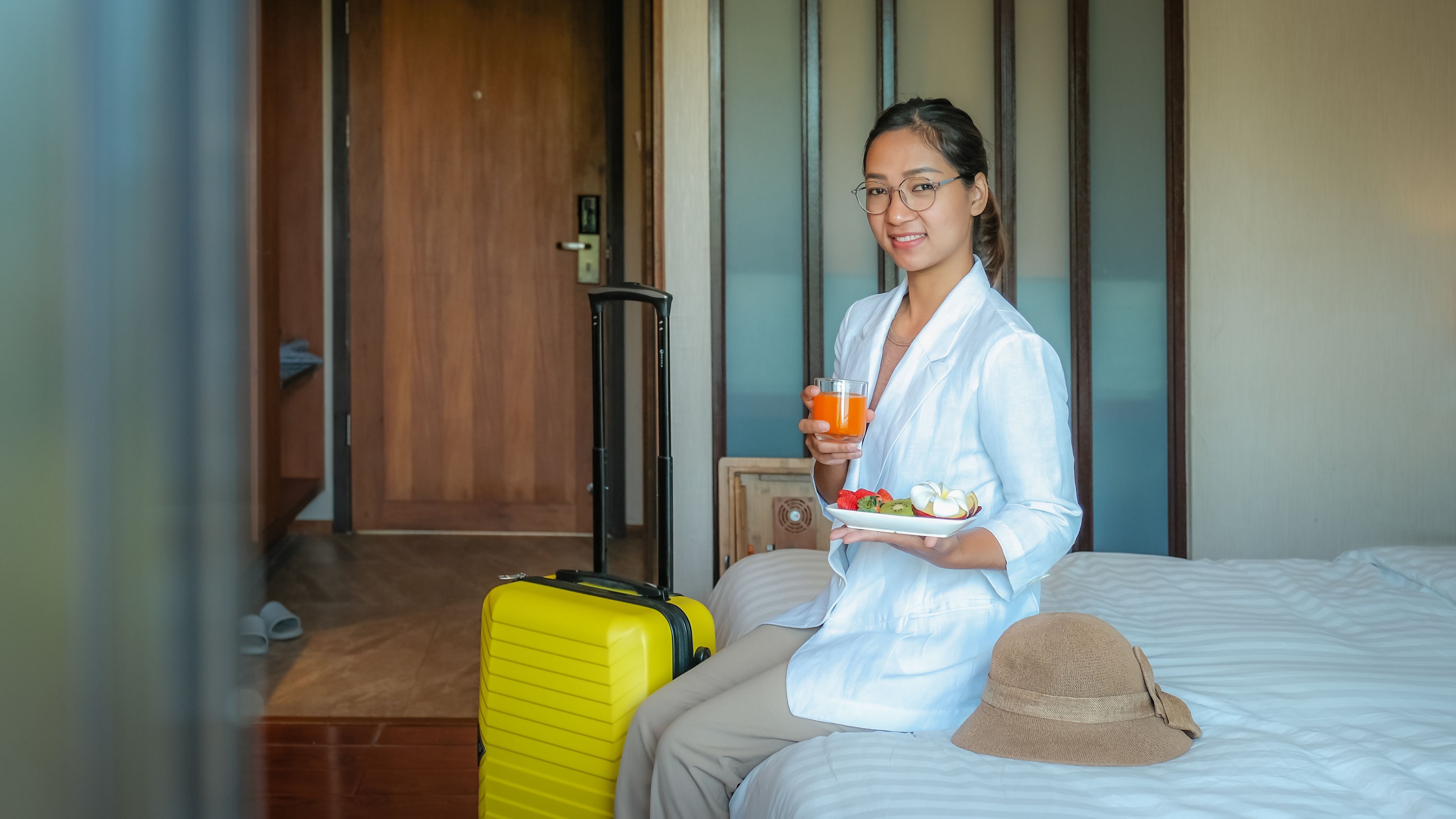  Ahli perniagaan makan buah-buahan dan minum jus oren di atas katil di bilik hotel mewah 
