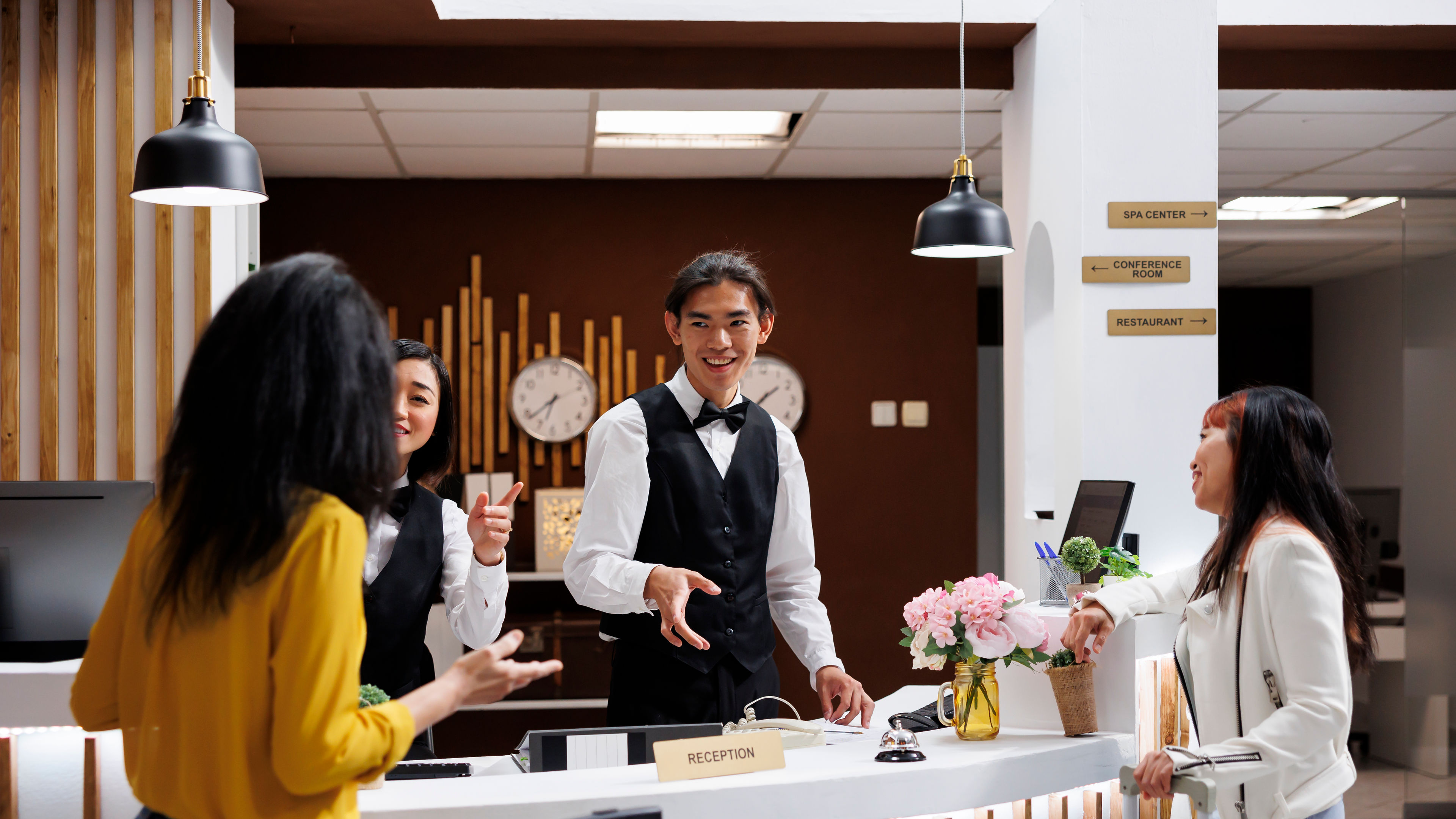 Young asian receptionist offering direction to arriving customer in lobby 
