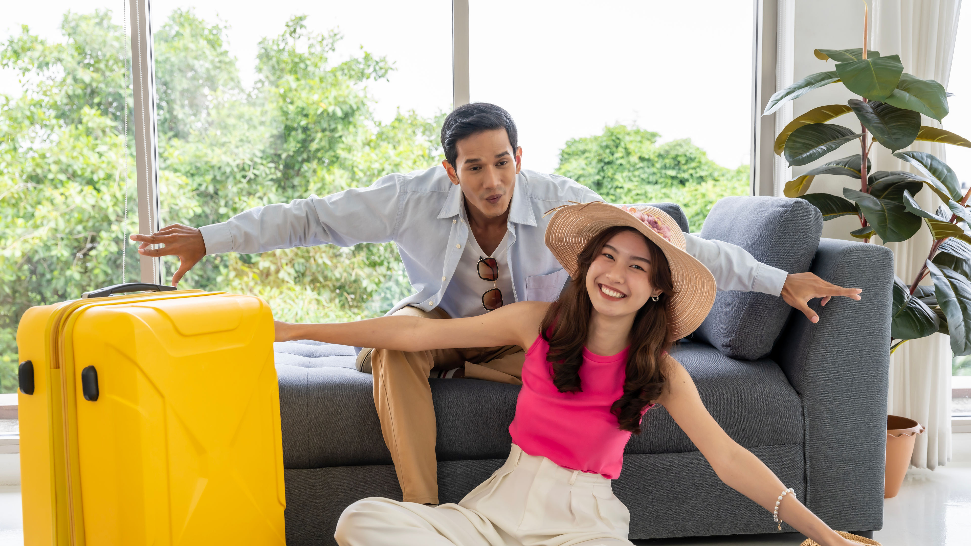 A happy Asian couple posing together beside a yellow trolley.