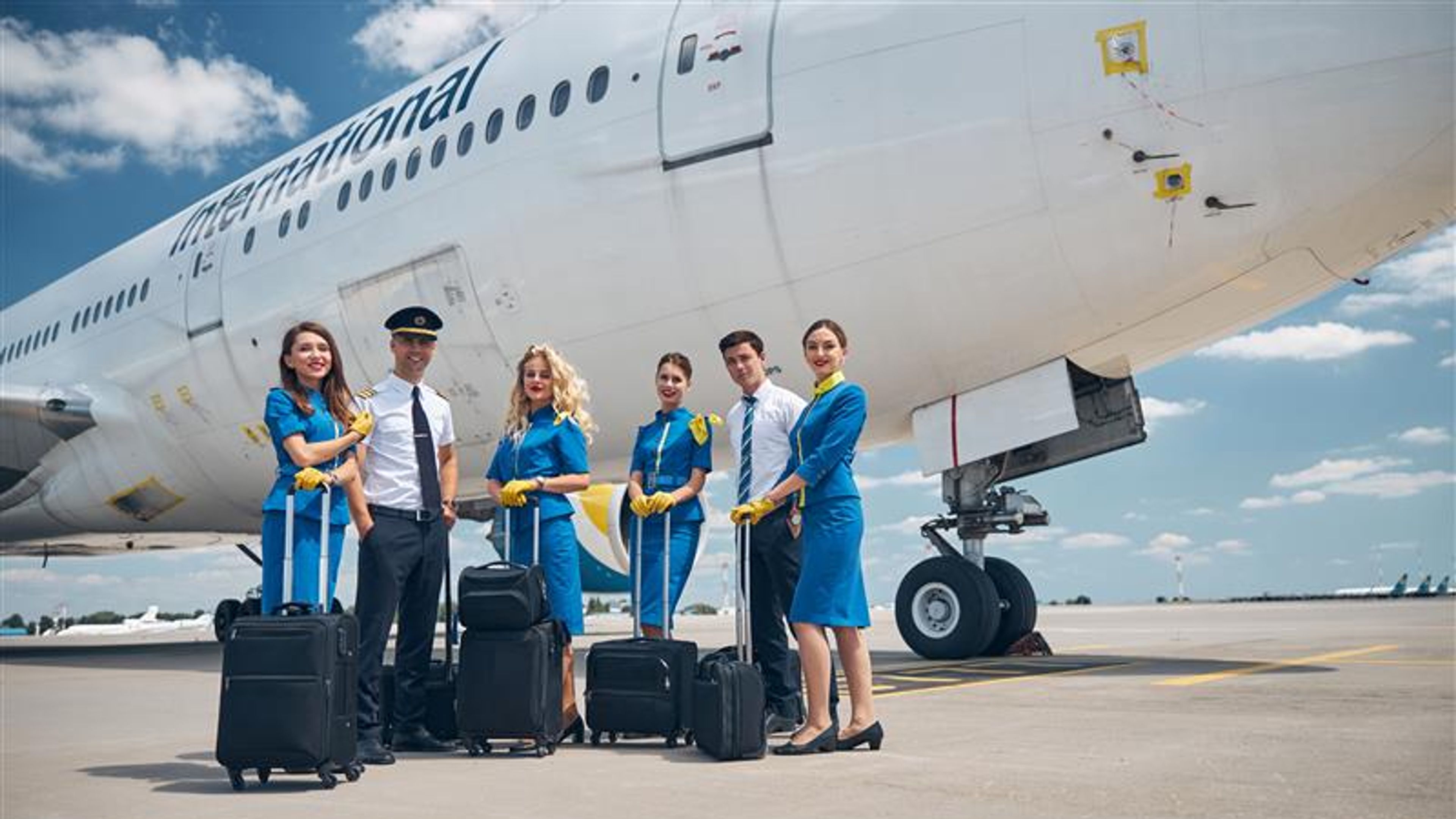 Aircrew members with travel bags standing by airplane