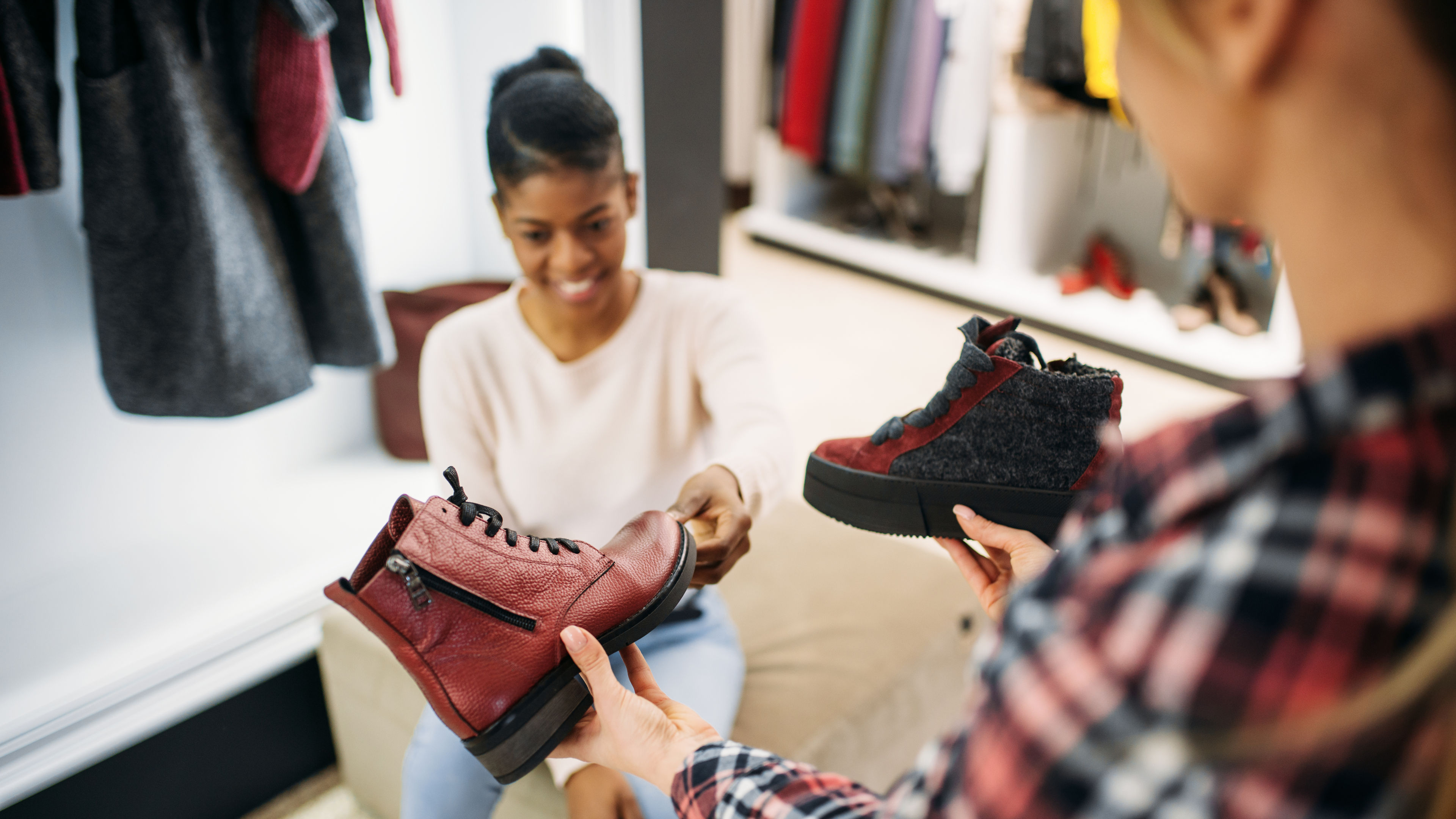 Two female friends trying on shoes from a shop.