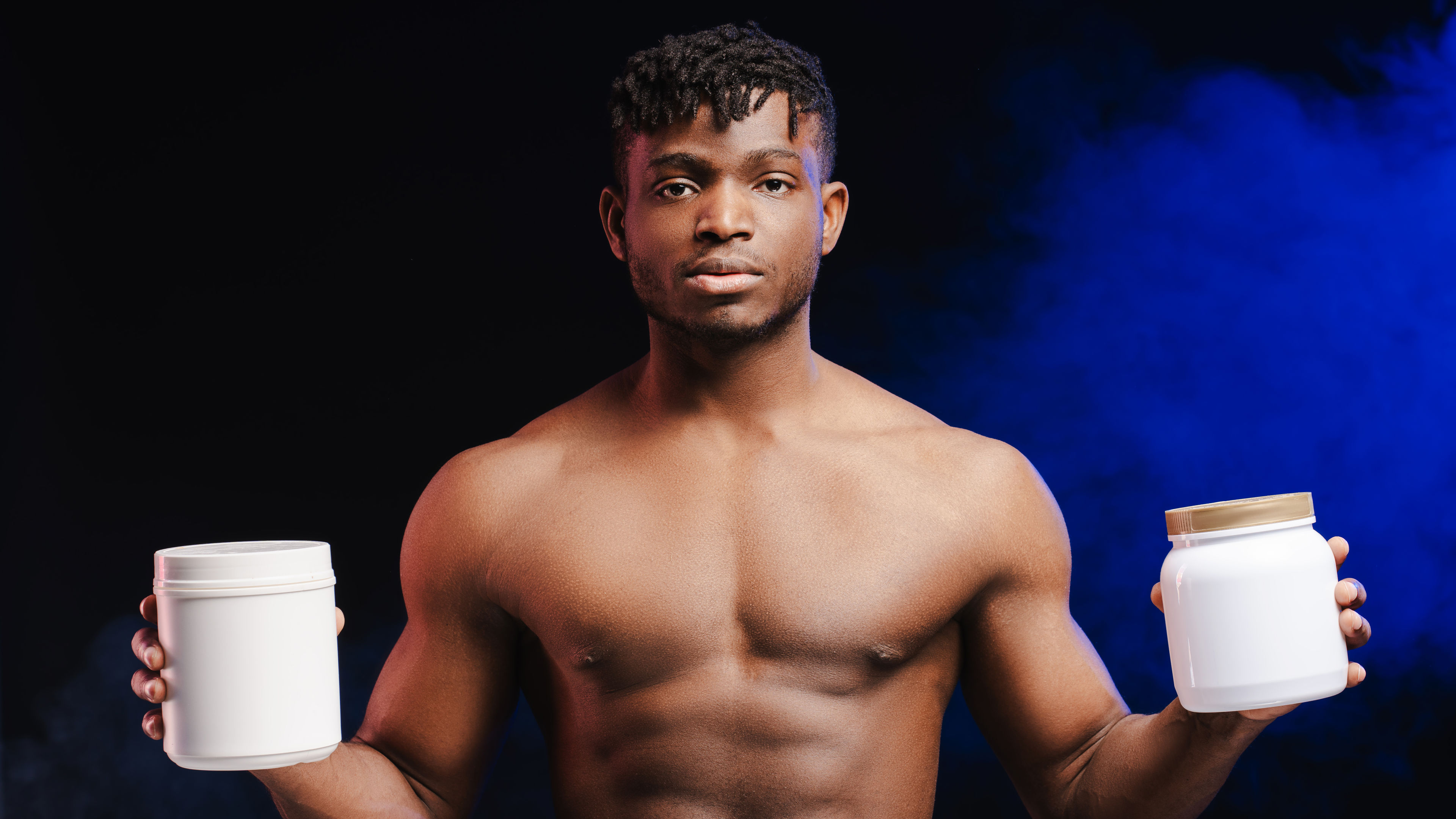 Serious African American man, sportsman with naked, pumped torso holding two white bottle mockup