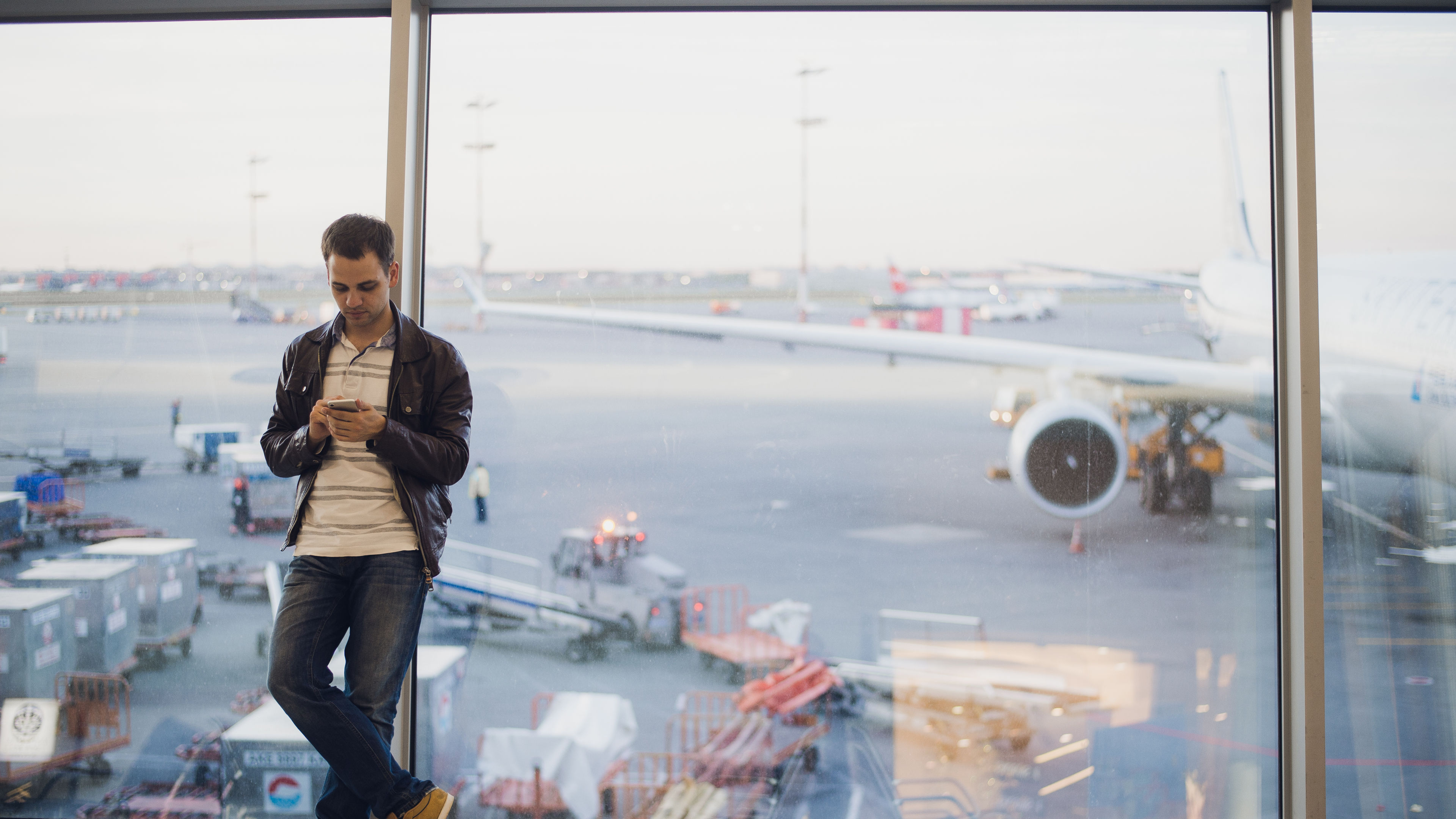 Young man using mobile phone and waiting for his flight.