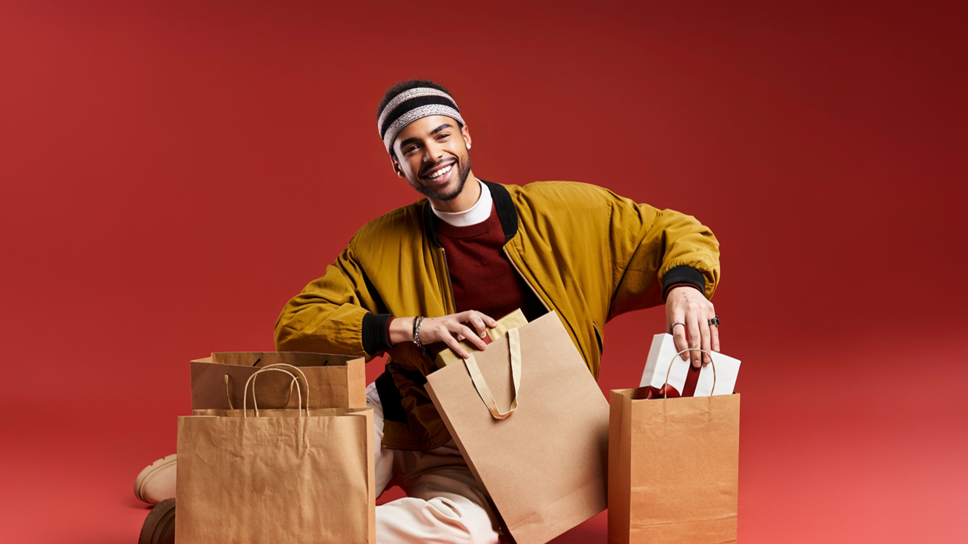 A stylish young man enjoys Black Friday shopping with bags in a studio setting