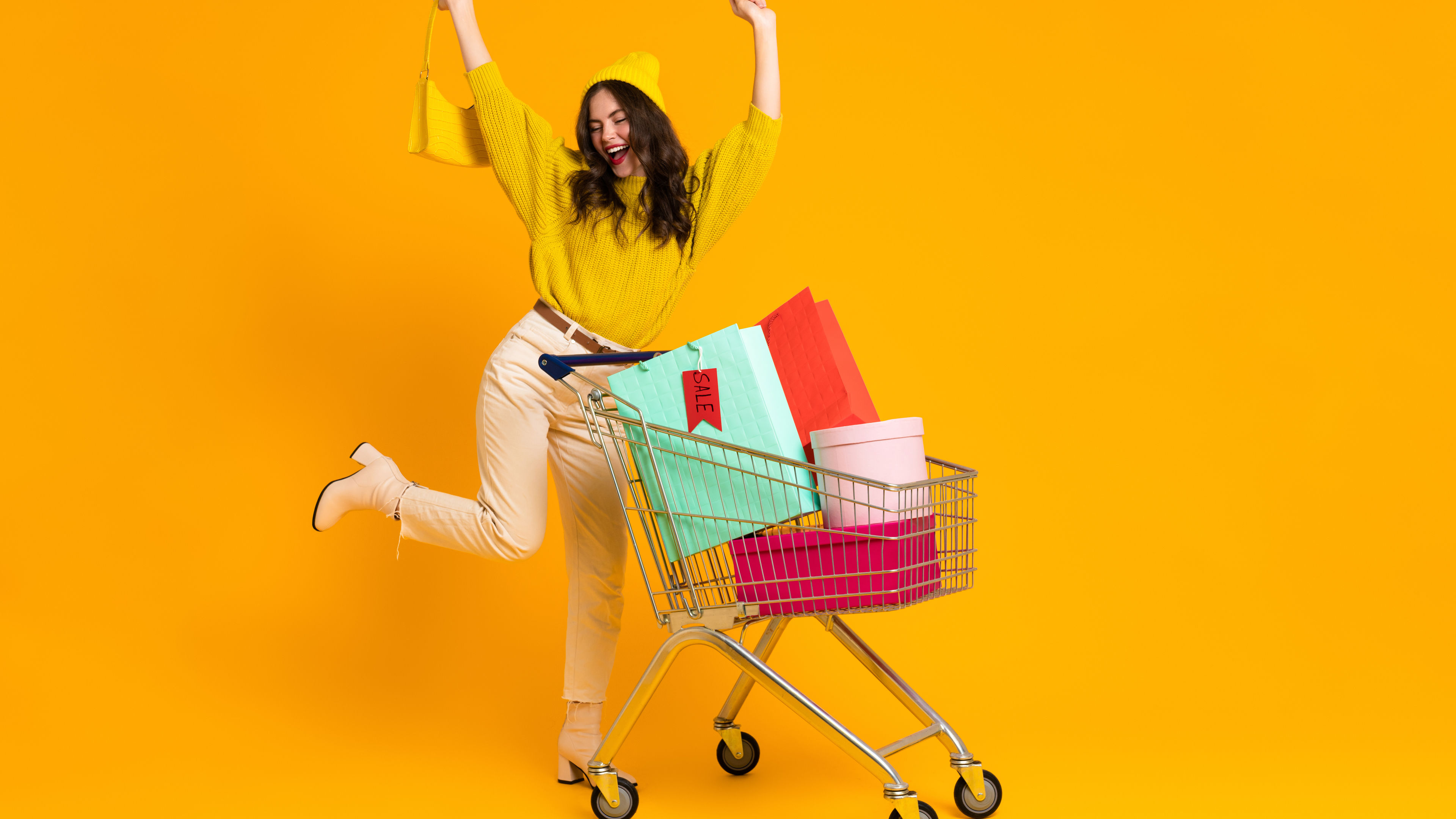 White woman making winner gesture while posing with shopping cart