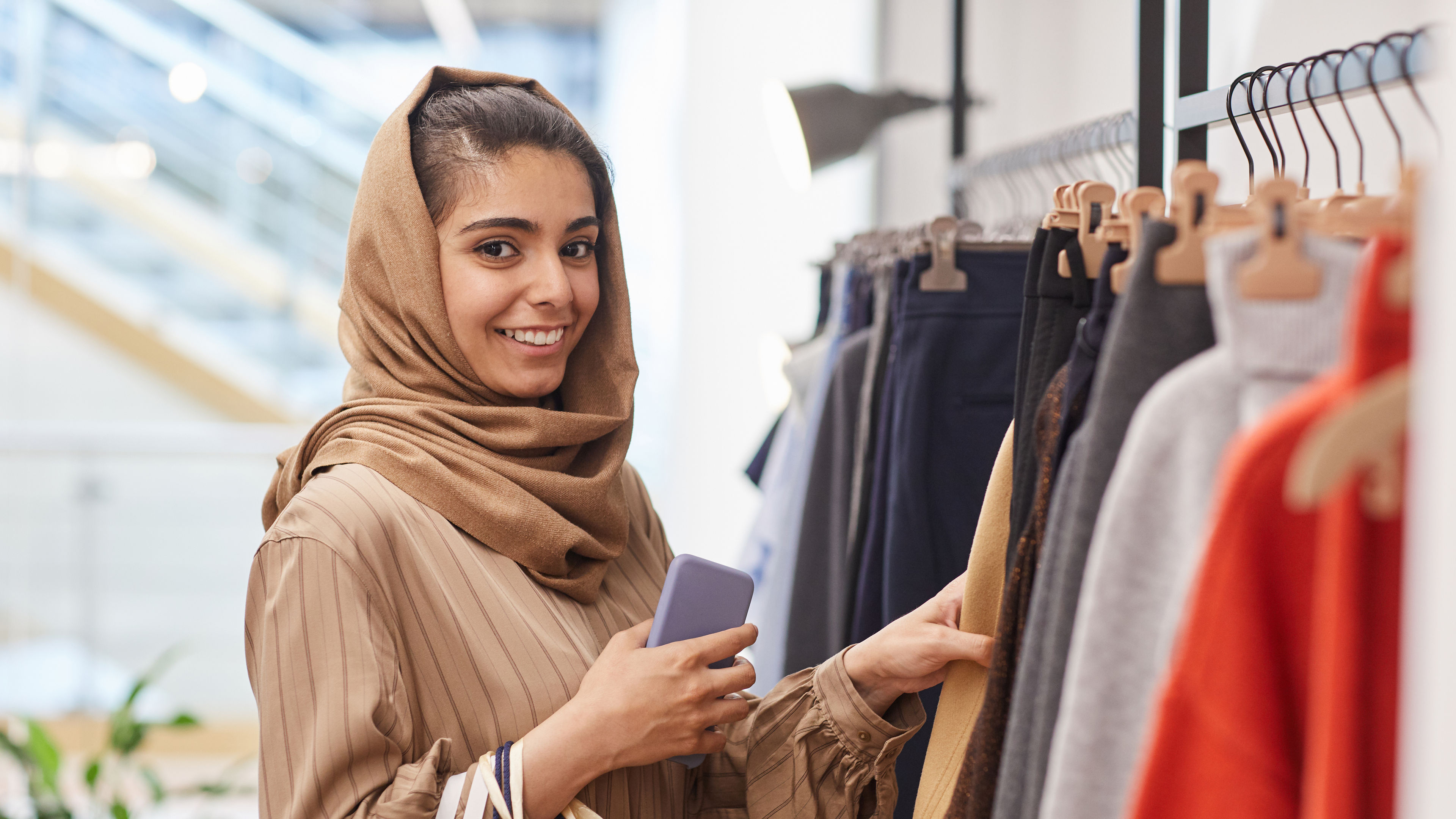 A Middle-Eastern woman shopping in a mall, striking a pose for a picture.