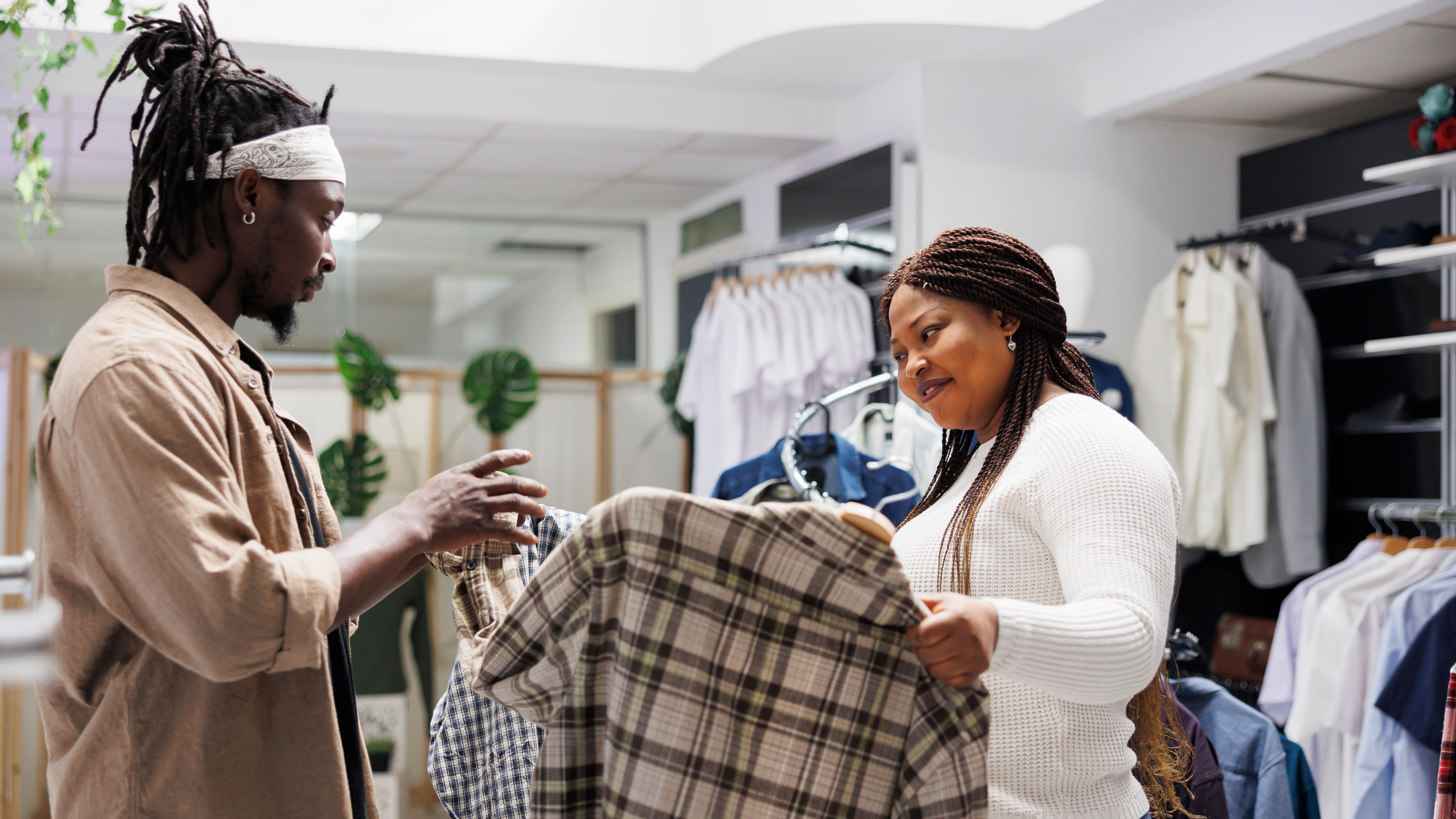 Friends trying on clothes and holding shirts to compare.