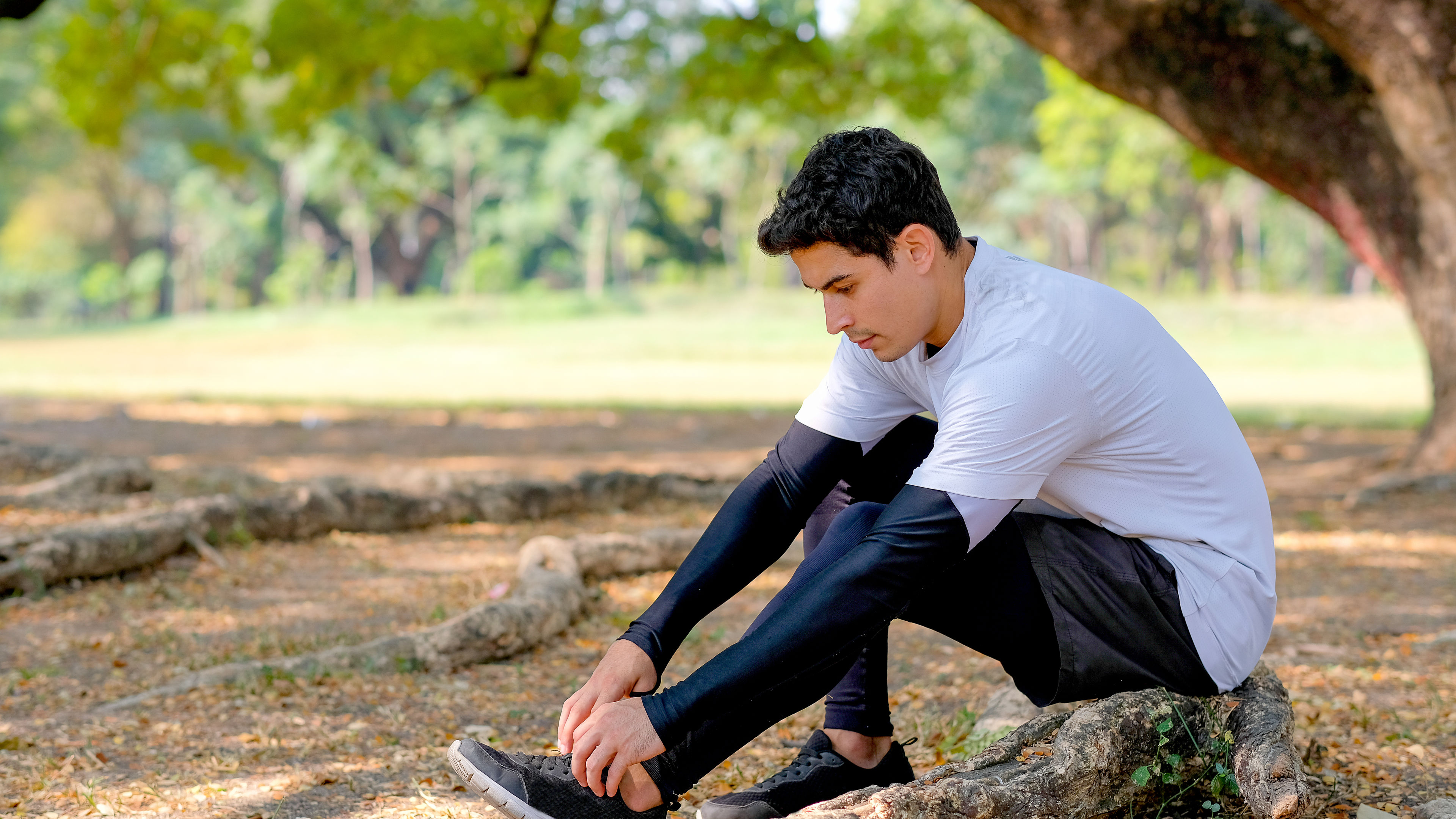 Sport man with white shirt and black legging tie shoelace