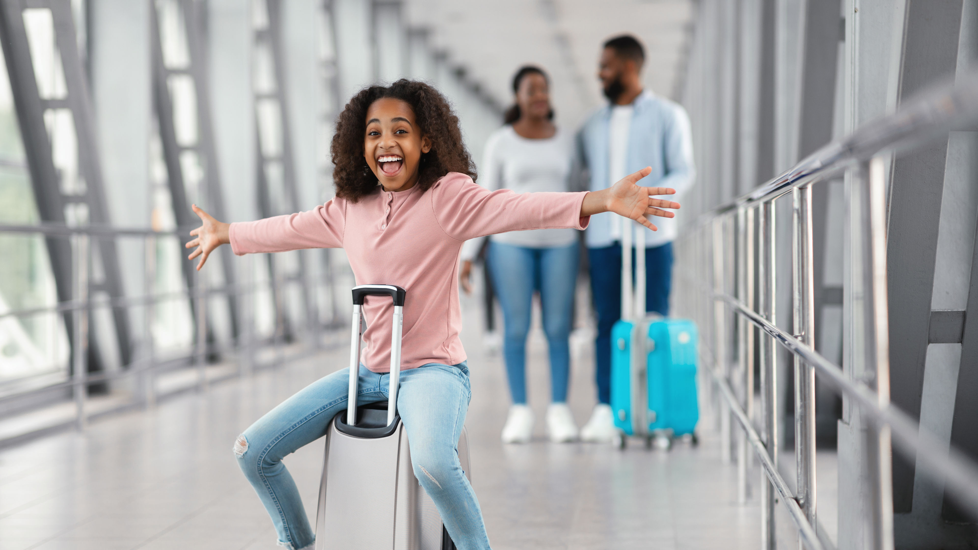 Happy black family traveling with kid, walking in airport.