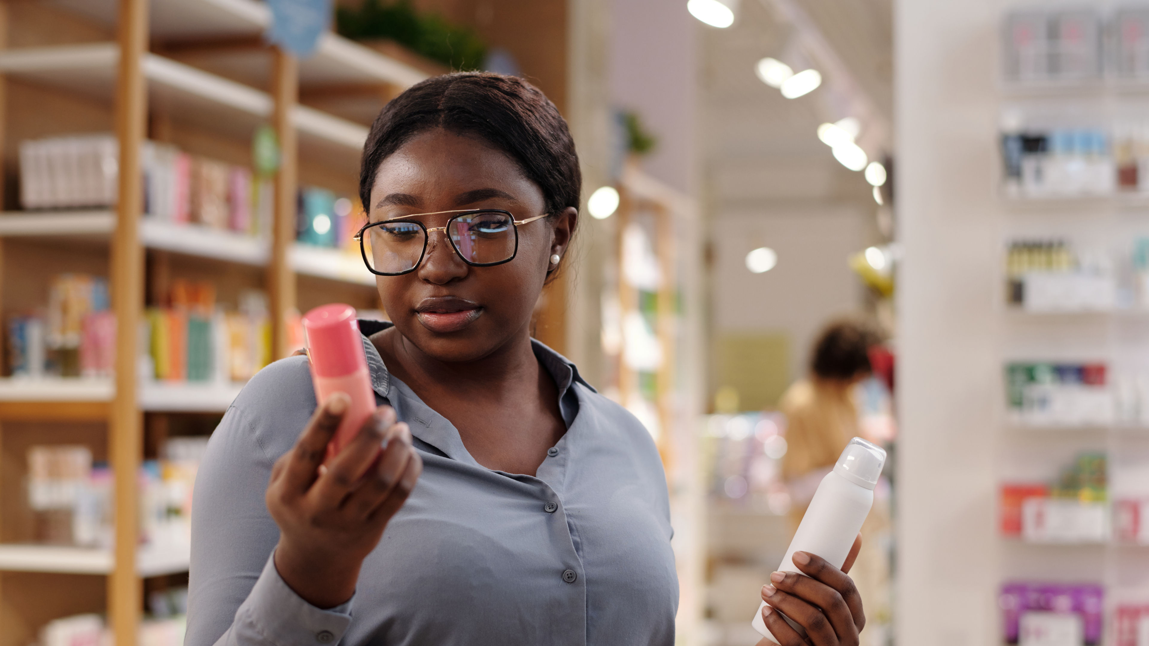 Woman in glasses examining skincare products in a store.