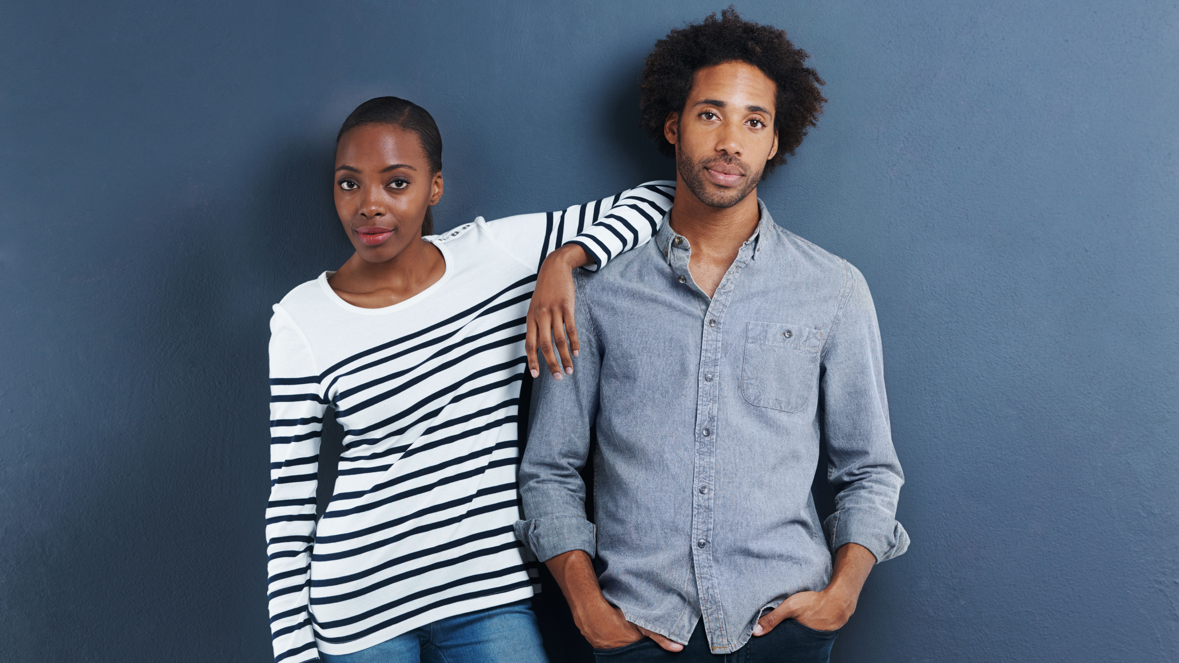 A stylish couple is wearing fashionable clothing, walking confidently together through the city streets, turning heads.