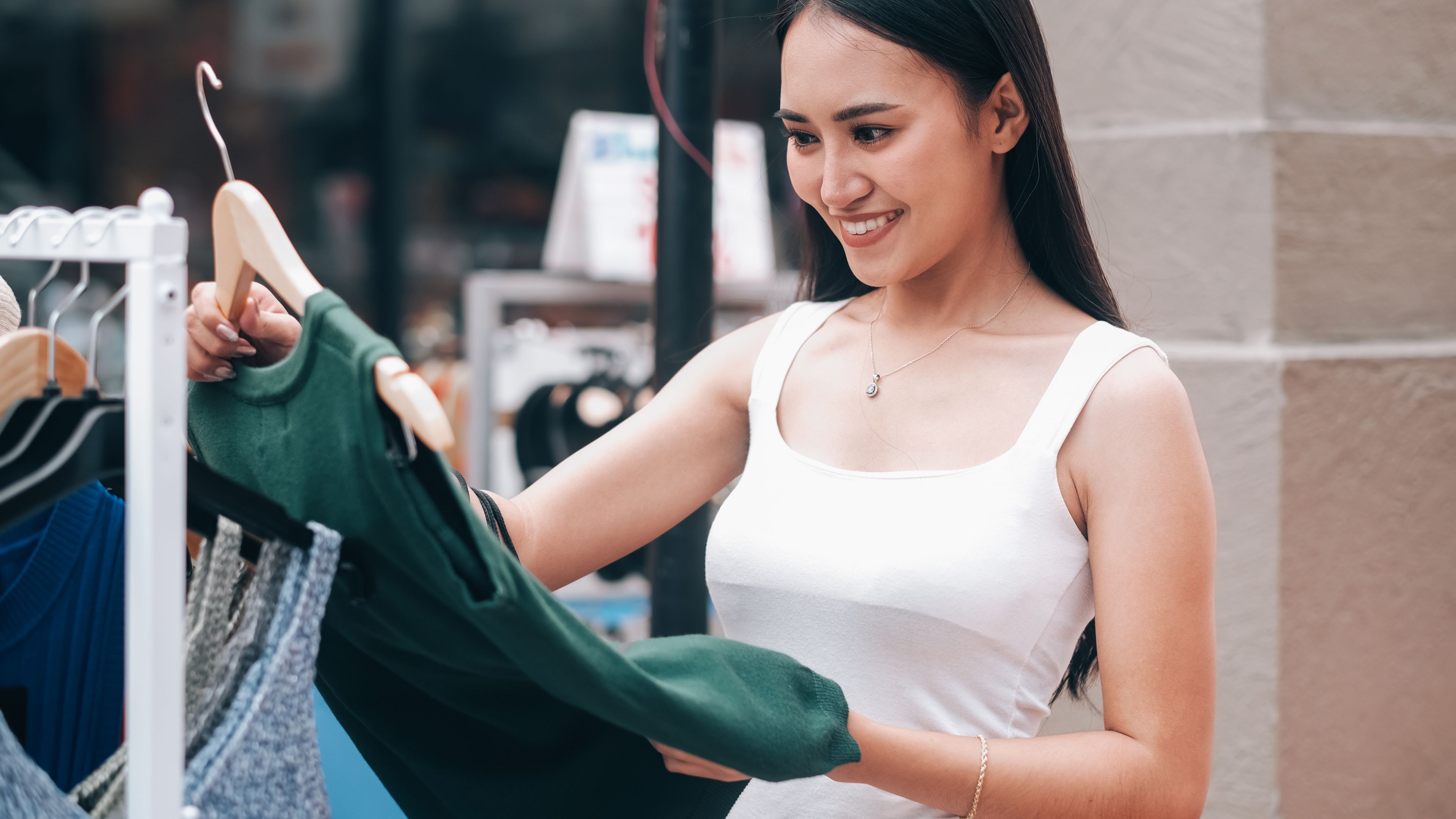 A woman holding a beautiful dress in her hand, deciding whether to try it on