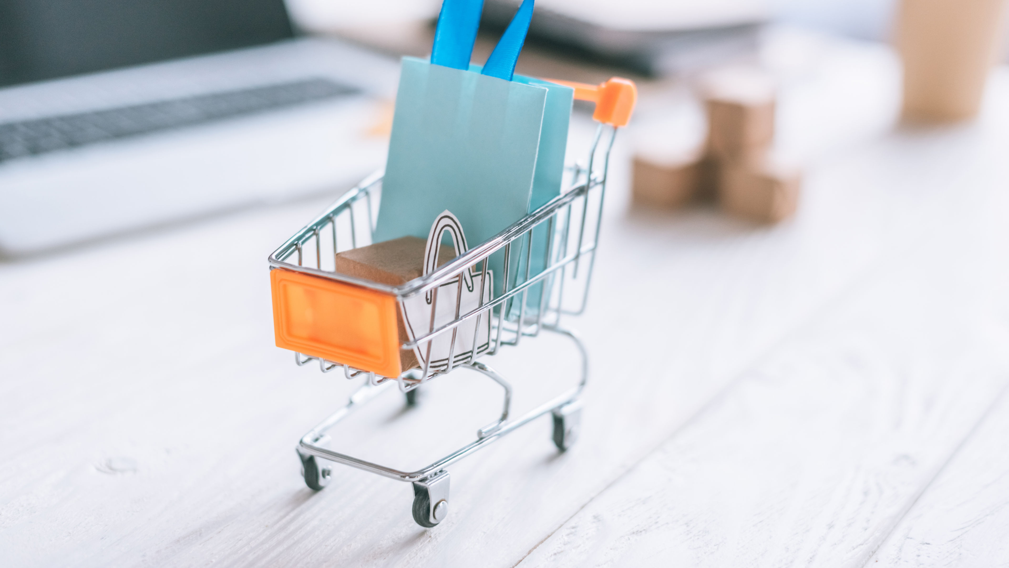 The image depicts a shopping cart with a blue bag and a box, symbolizing online shopping.