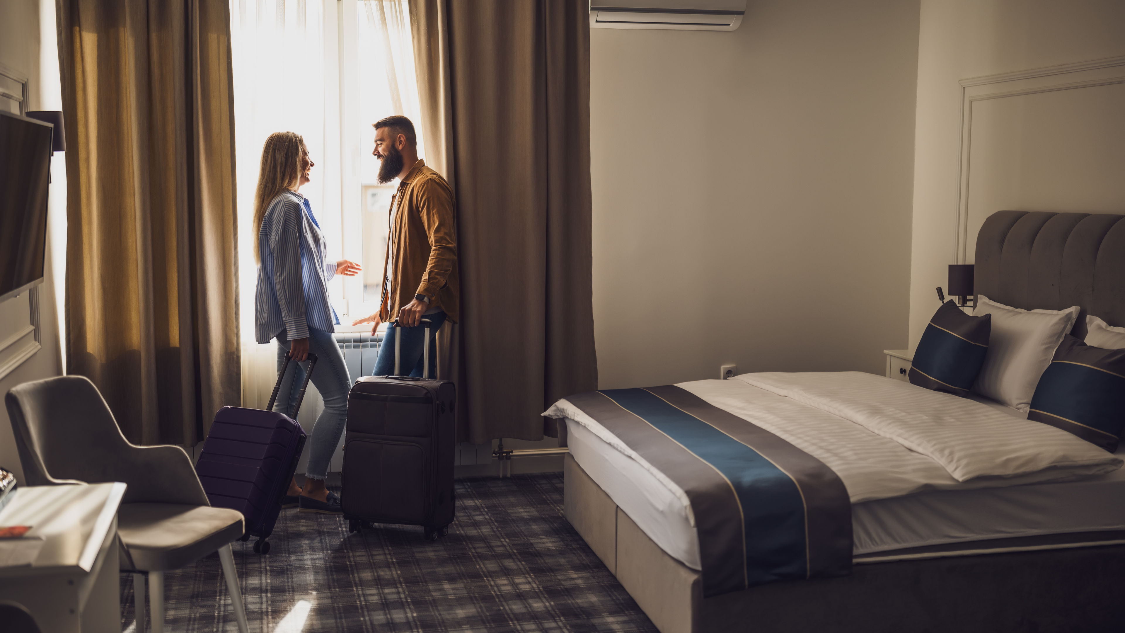 Tourist couple in hotel room with luggage beside.