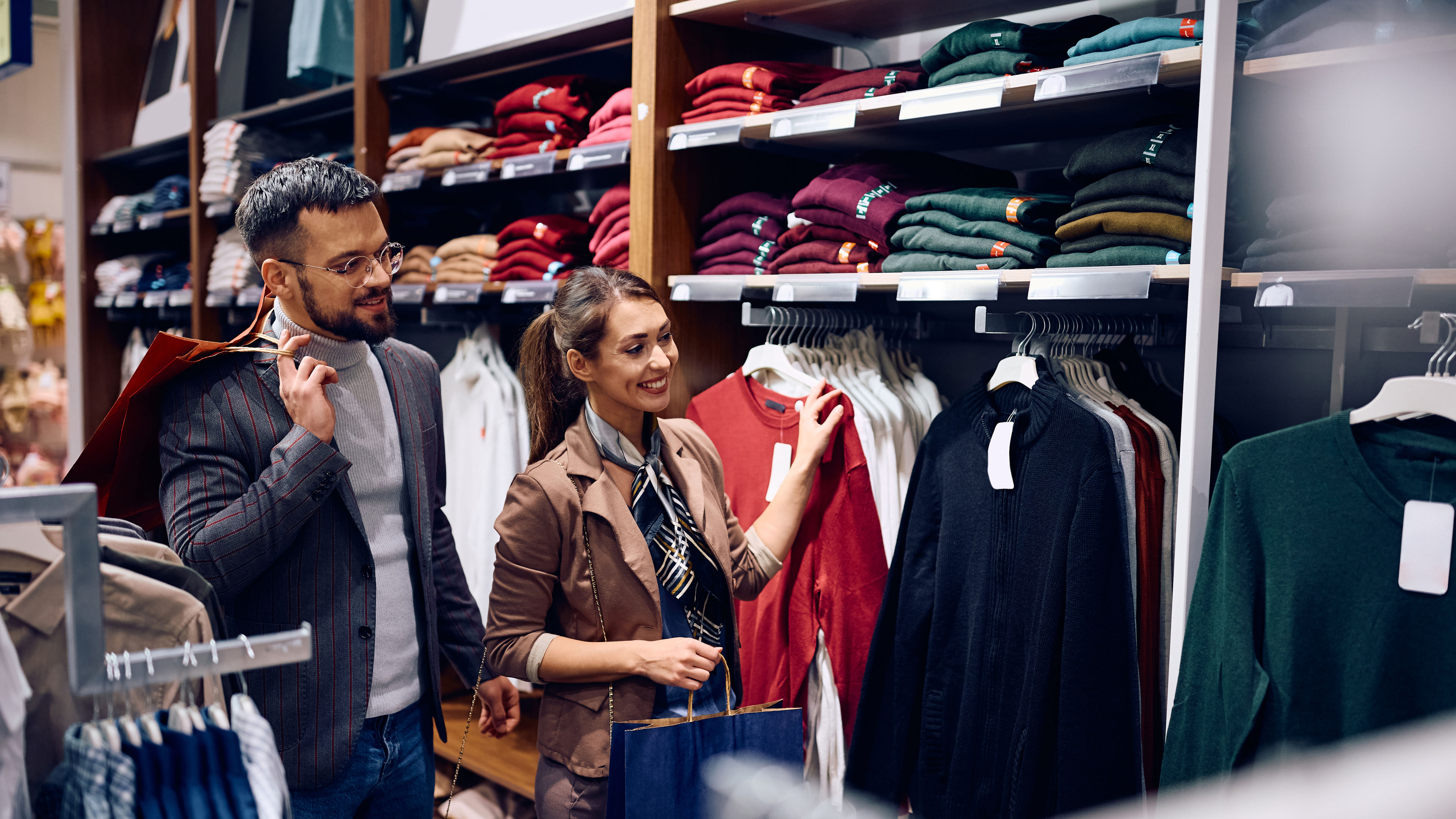 Happy woman and her boyfriend looking for new clothes in a shopping mall.