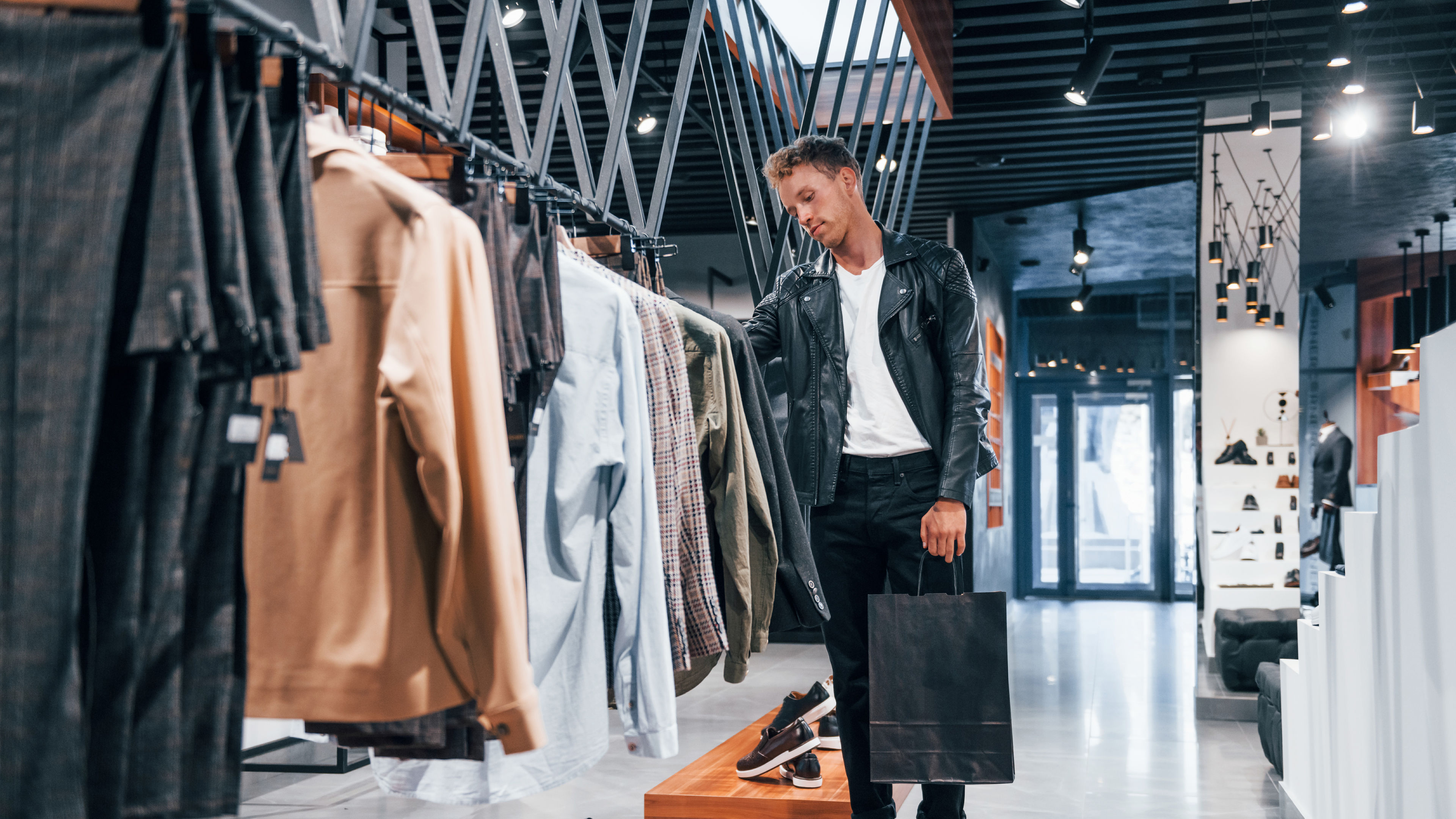 Young looking man checking clothes on a rack in a shop.